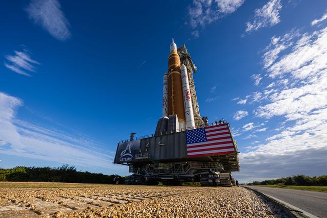 This image shows NASA’s SLS (Space Launch System) and Orion spacecraft rollin...