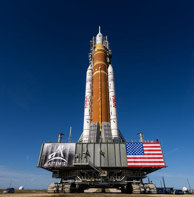 This image shows NASA’s SLS (Space Launch System) and Orion spacecraft rollin...