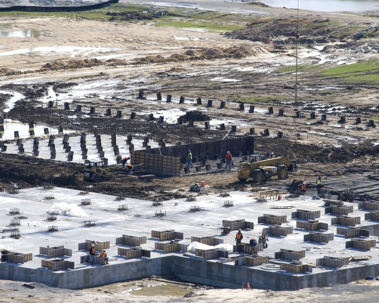 The concrete foundation placed Dec. 18 (foreground) for Stennis Space Center's future A-3 Test Stand has almost completely cured by early January, according to Bo Clarke, NASA's contracting officer technical representative for the foundation contract. By late December, construction on foundations for many of the test stand's support structures - diffuser, liquid oxygen, isopropyl alcohol and water tanks and gaseous nitrogen bottle battery - had begun with the installation of (background) `mud slabs.' The slabs provide a working surface for the reinforcing steel and foundation forms.
