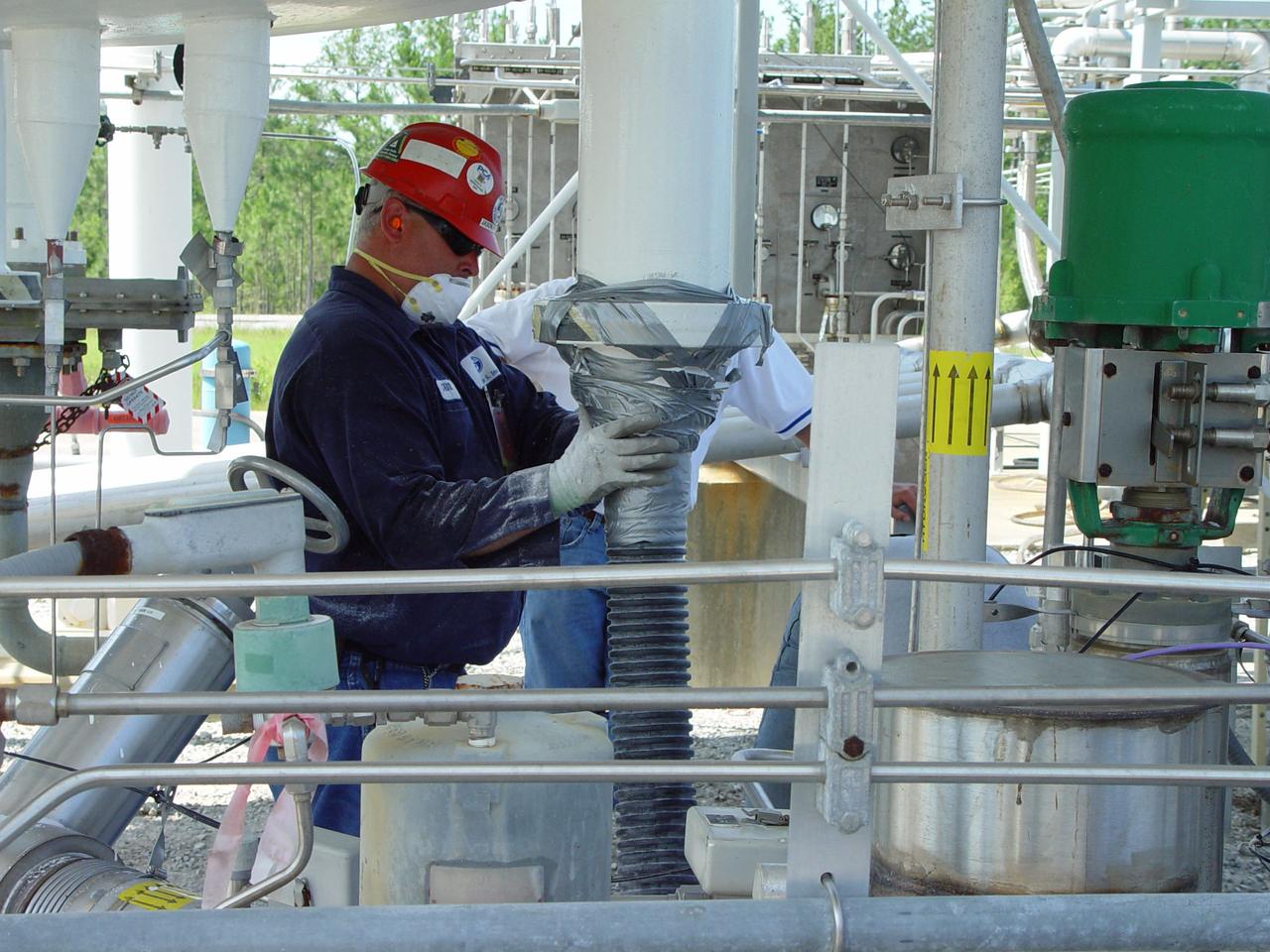 A worker removes Perlite insulation from a liquid hydrogen storage tank to replace it with glass bubble insulation.