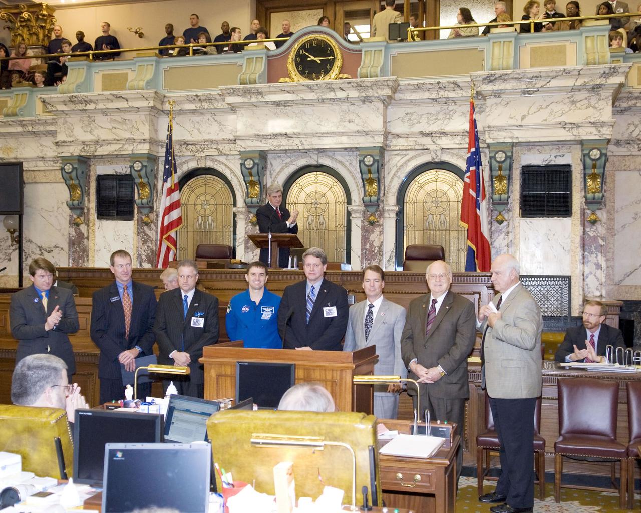 Astronaut Rex Walheim (center) speaks to members of the Mississippi House of Representatives in chambers during NASA Day at the Capitol in Jackson on Feb. 19. Walheim was joined at the podium by members of the Mississippi House of Representatives Gulf Coast delegation, as well as Stennis Space Center Director Gene Goldman (astronaut's immediate right) and NASA's Shared Services Center Director Rick Arbuthnot and Partners for Stennis Executive Director Tish Williams (astronaut's immediate left).