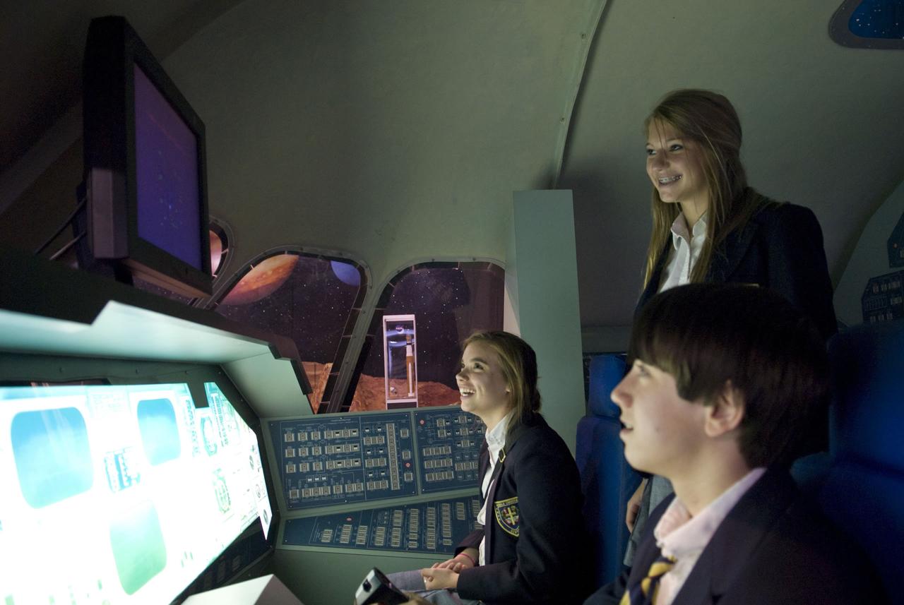 Erin Whittle, 14, (seated) and Brianna Johnson, 14, look on as Louis Stork, 13, attempts a simulated landing of a space shuttle at StenniSphere. The young people were part of a group from Mobile Christian School in Mobile, Ala., that visited StenniSphere on April 21.
