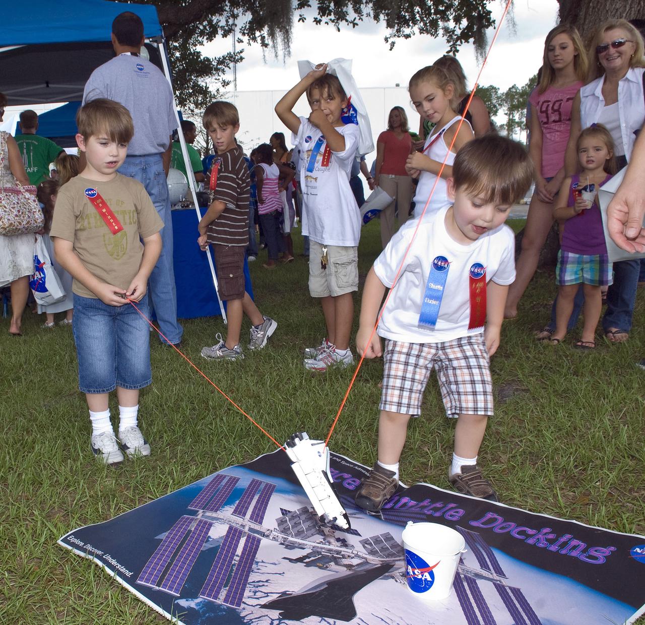 From left, Roman Valente, 6, tries his luck docking a toy shuttle while Nicholas Valente, 4, watches. The brothers are the sons of Andrew Valente of NASA.