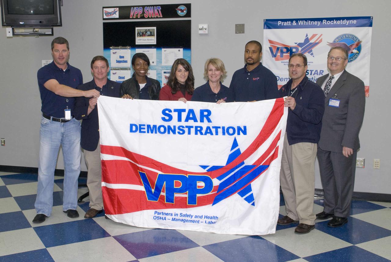 Pratt and Whitney Rocketdyne at NASA's John C. Space Center was presented its Voluntary Protection Programs (VPP) Star Demonstration banner by the Occupational Safety and Health administration (OSHA) during a Dec. 8 ceremony. Pratt Whitney Rocketdyne VPP Safe Working Action Team members Alan Howe (l to r), Mike McDaniel, April Page, Nyla Trumbach, Donna Pullman, Gary Simpson and Frank Pellegrino received the VPP Star Demonstration flag from OSHA Area Director Clyde Payne (right). OSHA established VPP in 1982 as a proactive safety management model so organizations and their employees could be recognized for excellence in safety and health.