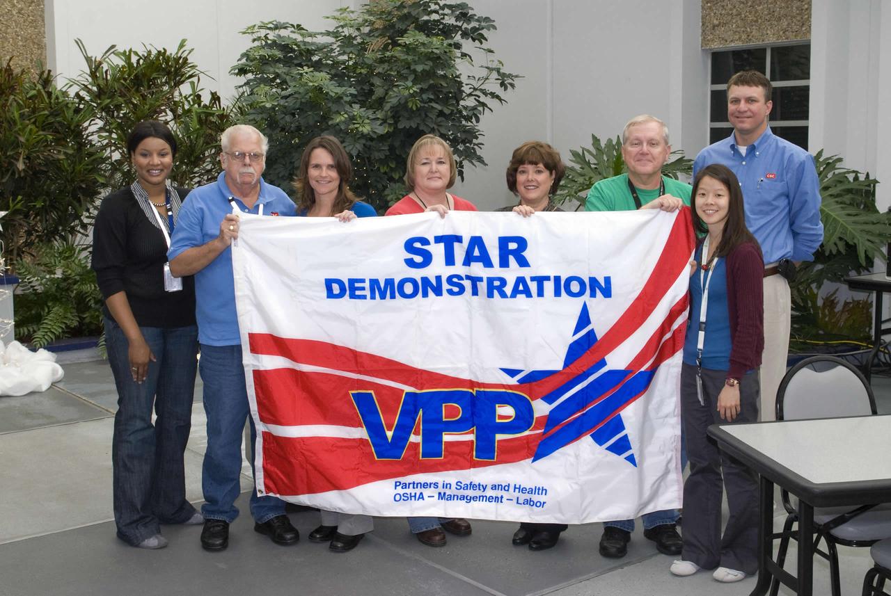 CSC Inc. at NASA's John C. Space Center was presented a Voluntary Protection Programs (VPP) Star Demonstration banner by the Occupational Safety and Health administration (OSHA) during a Dec. 9 ceremony. From left, CSC Employee Safety Committee members LaSonya Pulliam (l to r), Jim Sever, Stacy Brunson, Debbie Duke, Sheliah Wilson, Fred Voss and Beth Nguyen, and CSC Program Manager Tony Lisotta received the banner. OSHA established VPP in 1982 as a proactive safety management model so organizations and their employees could be recognized for excellence in safety and health.