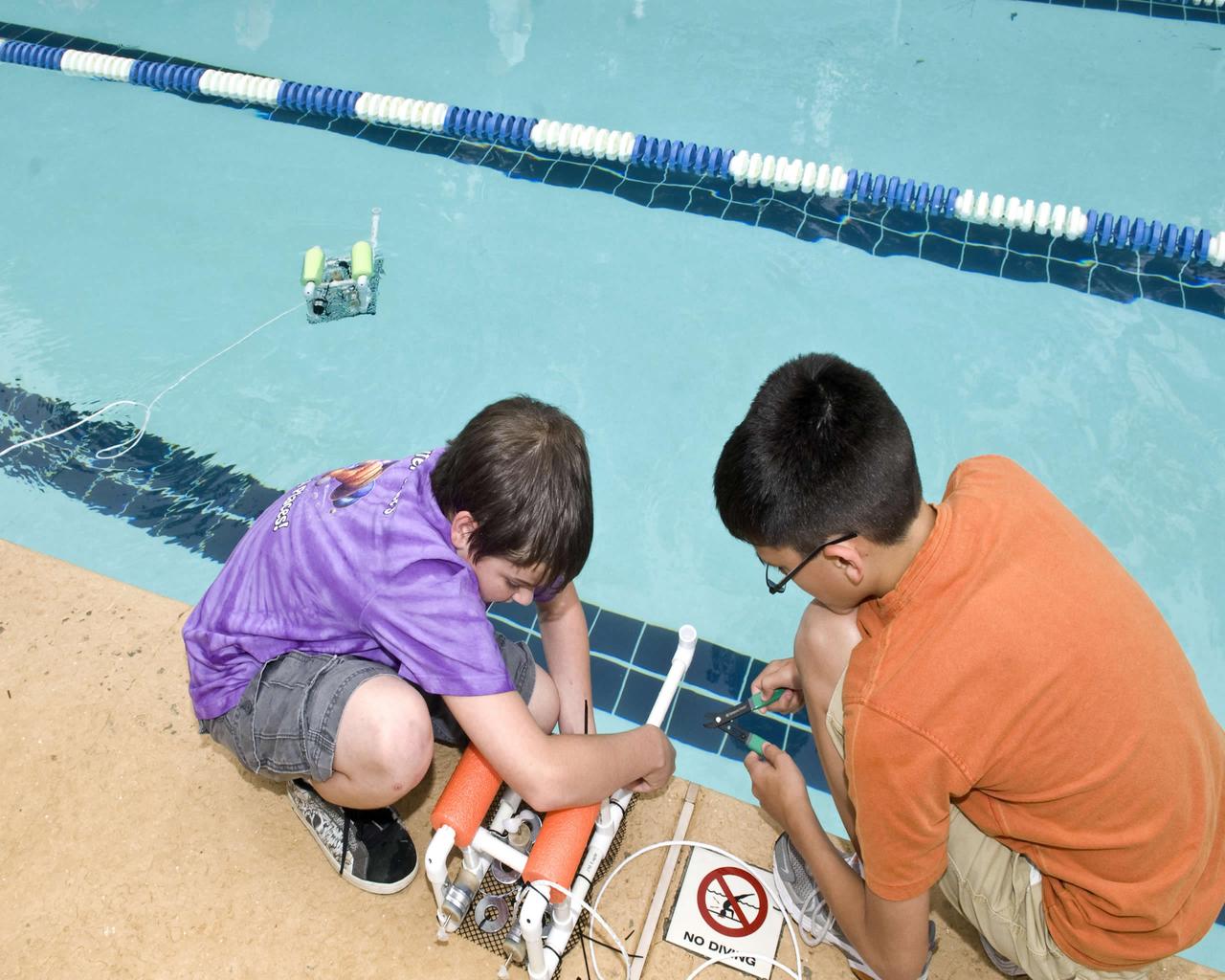 Ian Tonglet, 13, (left) and Seth Malley, 13, both of Picayune, Miss., and both participants in the 2010 Astro Stars session at Stennis Space Center, work with an underwater robot during a camp activity June 29. NASA joined with the U.S. Navy for the underwater robotics exercise involving Sea Perch robots, which are simple, remotely operated underwater vehicles made from PVC pipe and other inexpensive, easily available materials. During the Stennis exercise, students used robots constructed earlier in the day to maneuver underwater and collect plastic rings, as seen to the left of Tonglet. Astro STARS (Spaceflight, Technology, Astronomy & Robotics @ Stennis) is a science and technology camp for 13-15 year olds.
