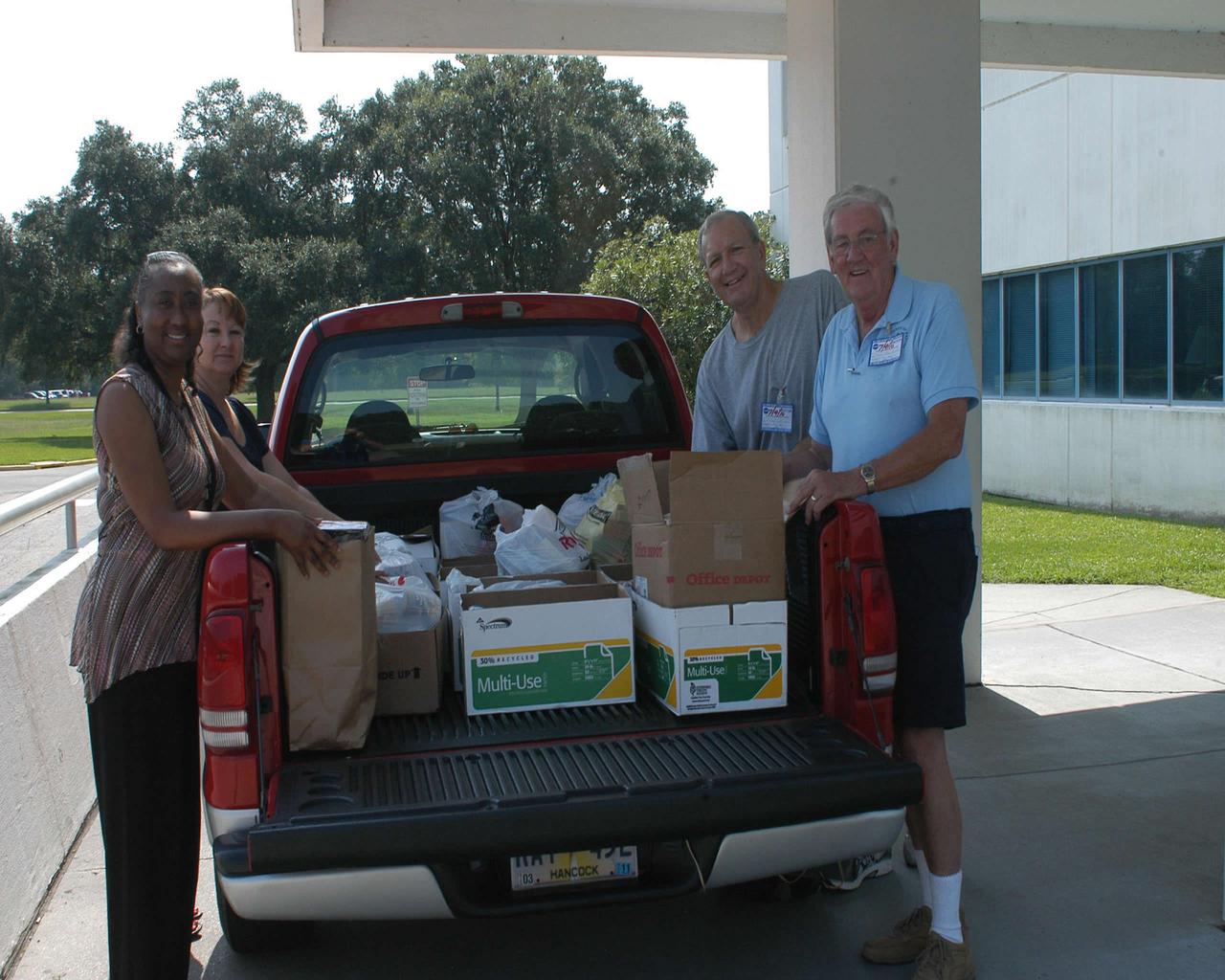 Cabrina Bell (l to r) and Jeanie Frederick with the Stennis Space Center Office of Human Capital help Hancock County Food Pantry representatives Edward Catone and Frank Manchester load collected food items July 9 as part of the 2010 Feds Feed Families campaign. The second annual national food drive was launched last month and involves federal agencies and employees across the country. Organizers hope to collect 1.2 million pounds of food items throughout the summer.