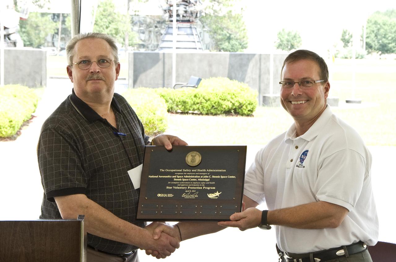 Stennis Space Center Deputy Director Rick Gilbrech (right) accepts a plaque designating the test facility as a Voluntary Protection Program Star site. Presenting the plaque is Clyde Payne, area director for the Occupational Safety and Health Administration in Jackson, Miss. OSHA established VPP in 1982 as a proactive safety management model to recognize excellence in safety and health. Since then, more than 2,000 organizations have been designated VPP Star sites. To reach that goal, an organization must demonstrate comprehensive and successful safety and health management programs in the workplace.