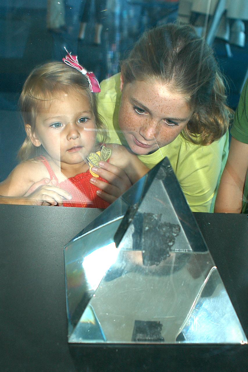 Clare Johnston, 10, and Eden Landis, 3, stare in wonder at the moon rock on display at the INFINITY at NASA Stennis Space Center visitor center and museum. The children toured INFINITY exhibits during ribbon-cutting activities for the facility April 11, 2012.