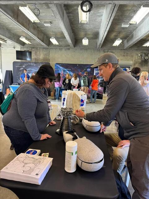 NASA mechanical test operations engineer Briou Bourgeois speaks with a visitor to the NASA Stennis booth during solar eclipse activities at the Indianapolis Motor Speedway in Indiana on April 8.