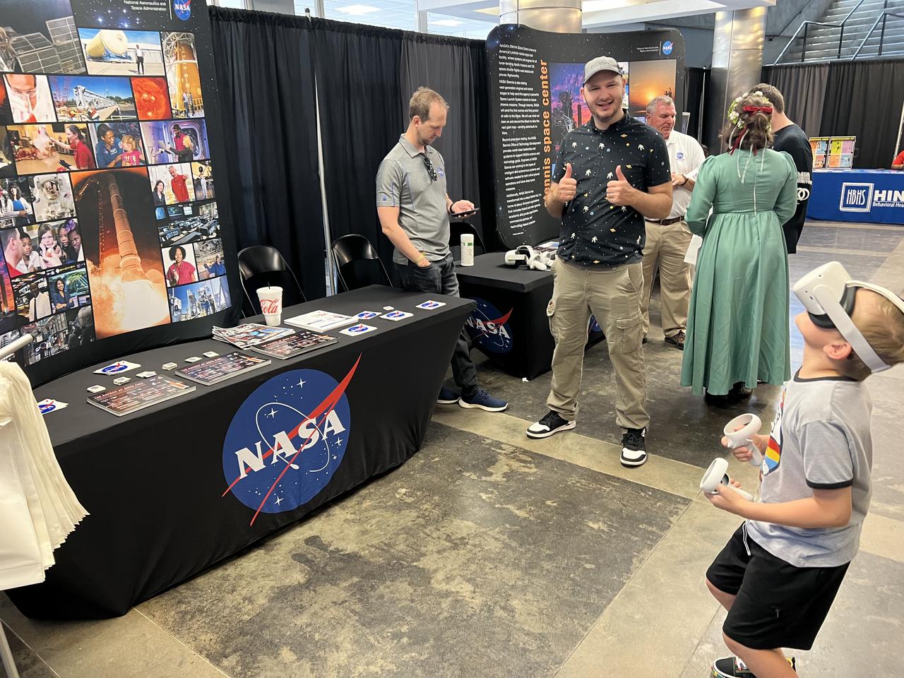 NASA engineer Steve Helmstetter, center, gives a thumbs up on June 22 at the Mississippi Comic Convention in Jackson, Mississippi, as a young fan has a virtual reality experience in space.
