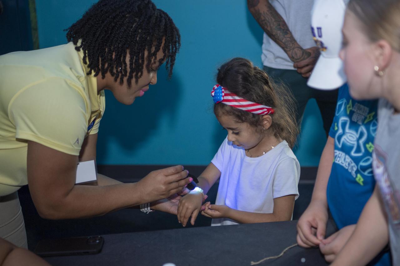 NASA Public Affairs Specialist Samone Wilson, left, uses a solar bead activity to teach a young visitor to the Audubon Aquarium in New Orleans about skin protection on July 5. NASA hosted an information/interactive exhibit at the aquarium in conjunction with NASA activities at the 30th annual ESSENCE Fest in New Orleans during the Fourth of July weekend.