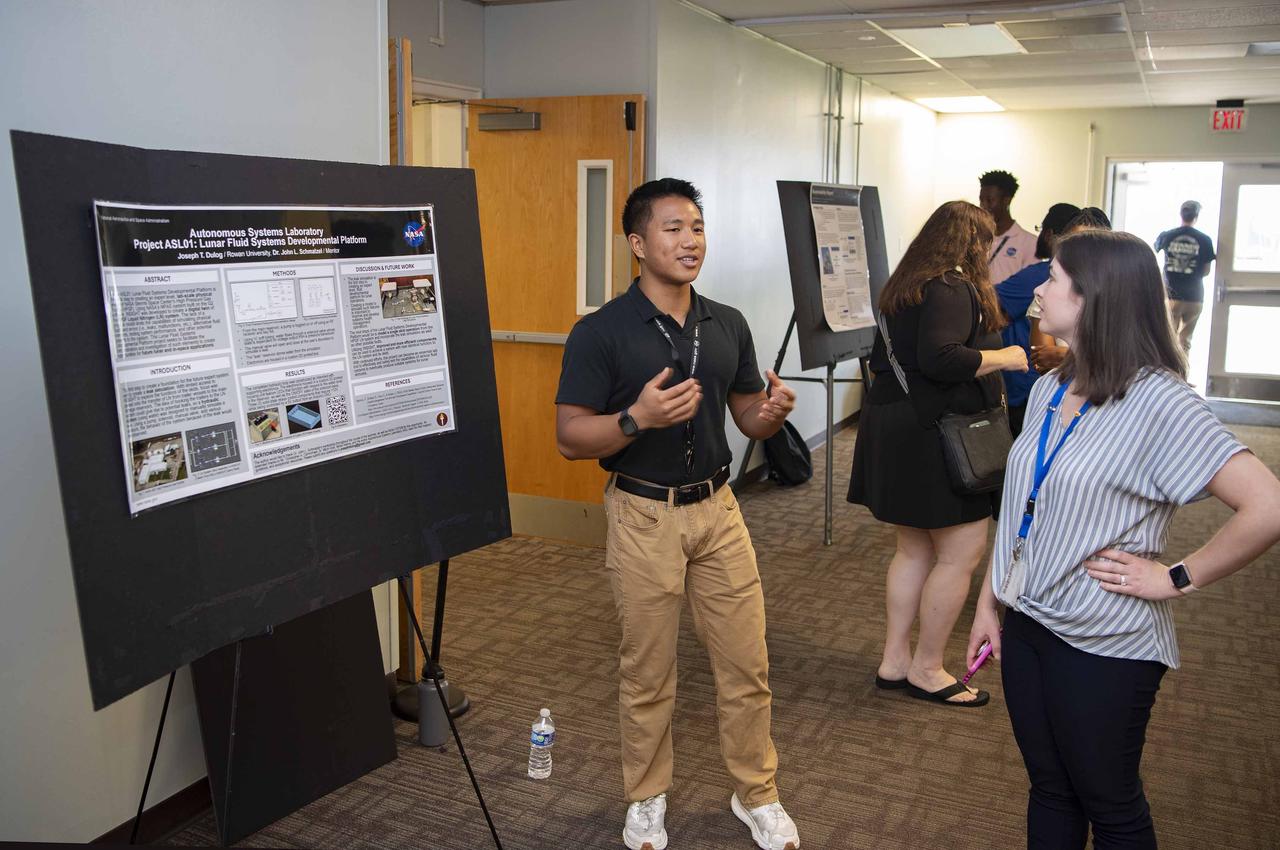 NASA Stennis summer intern Joseph Dulog, left, shares about his work on a lunar fluid systems developmental platform during an Aug. 7 event hosted by the Office of STEM Engagement. Dulog, a student at Rowan University in Glassboro, New Jersey, worked with the NASA Stennis Autonomous Systems Laboratory. The poster symposium highlighted research topics, including propulsion test operations, lunar robotics, autonomous systems, STEM education, and more. NASA’s Office of STEM Engagement paid internships allow high school and college-level students to contribute to the agency’s mission to advance science, technology, aeronautics, and space exploration.