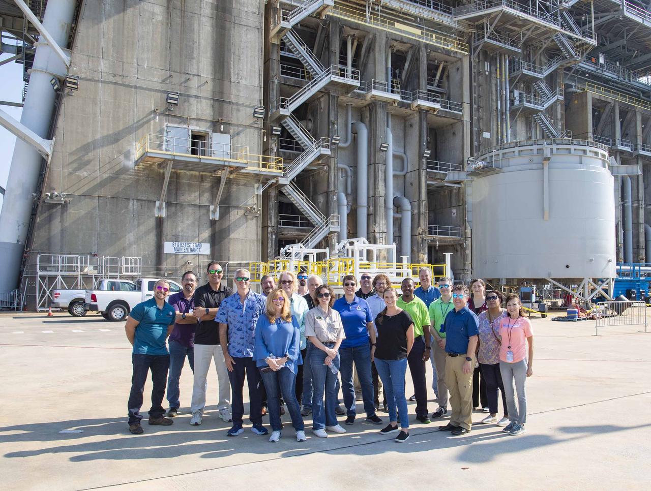NASA and contractor representatives working with NASA’s Rocket Propulsion Test Program Office stand at the base of the Thad Cochran Test Stand during a tour of the test complex on Aug. 15 at NASA’s Stennis Space Center near Bay St. Louis, Mississippi. The program office hosted a Risk Workshop and Program Management Review meeting at NASA Stennis on Aug. 13-15. The representatives are from NASA Stennis; NASA’s Neil Armstrong Test Facility in Sandusky, Ohio; NASA’s Michoud Assembly Facility in New Orleans; NASA’s Marshall Space Flight Center in Huntsville, Alabama; NASA’s Wallops Flight Facility in Virginia; and NASA Headquarters in Washington. NASA Stennis is preparing the Thad Cochran Test Stand (B-2) to test the exploration upper stage, which will fly on future SLS (Space Launch System) missions as NASA continues its mission of exploring the secrets of the universe for the benefit of all. The upper stage is being built at NASA Michoud as a more powerful second stage to send the Orion spacecraft to deep space. It is expected to fly on the Artemis IV mission. Before that, it will be installed on the test stand at NASA Stennis to undergo a series of Green Run tests of its integrated systems to demonstrate it is ready to fly.