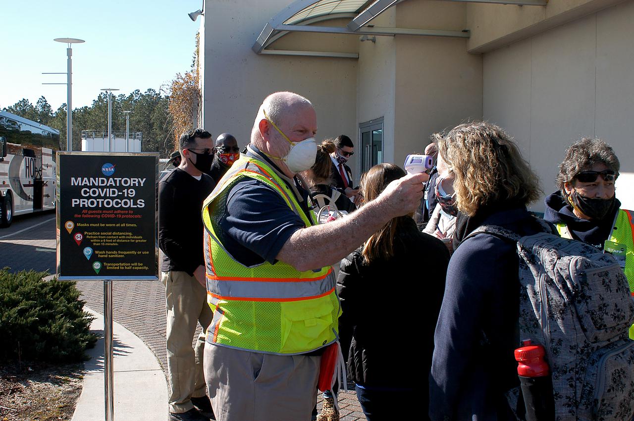 A staff member administers a COVID-19 temperature check to media and guests arriving to view the Green Run hot fire test of the core stage for NASA’s Space Launch System (SLS) rocket at Stennis Space Center near Bay St. Louis, Mississippi, on Saturday, January 16, 2021. NASA conducted a hot fire test of the core stage’s four RS-25 engines on the B-2 Test Stand at Stennis. Scheduled for as long as eight minutes, the engines fired for a little more than one minute to generate a combined 1.6 million pounds of thrust, just as will occur during an actual launch. The hot fire is the final test of the Green Run test series, a comprehensive assessment of the SLS core stage prior to launching the Artemis I mission to the Moon.