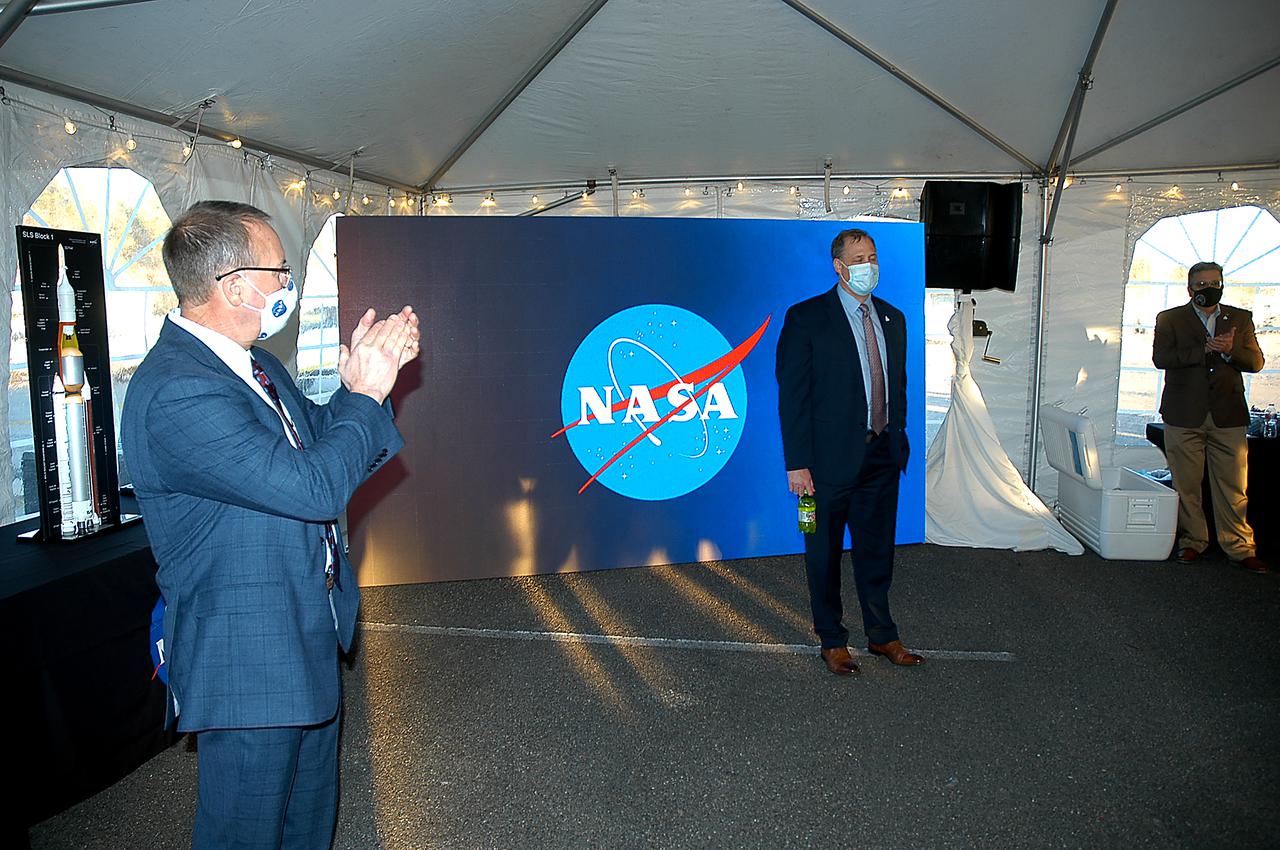 Outgoing NASA Administrator Jim Bridenstine (right) receives a round of applause from Stennis Director Rick Gilbrech and guests for comments following the Green Run hot fire test of the core stage for NASA’s Space Launch System (SLS) rocket at Stennis Space Center near Bay St. Louis, Mississippi, on Saturday, January 16, 2021. NASA conducted a hot fire test of the core stage’s four RS-25 engines on the B-2 Test Stand at Stennis. Scheduled for as long as eight minutes, the engines fired for a little more than one minute to generate a combined 1.6 million pounds of thrust, just as will occur during an actual launch. The hot fire is the final test of the Green Run test series, a comprehensive assessment of the SLS core stage prior to launching the Artemis I mission to the Moon. (NASA/Michael Badon)