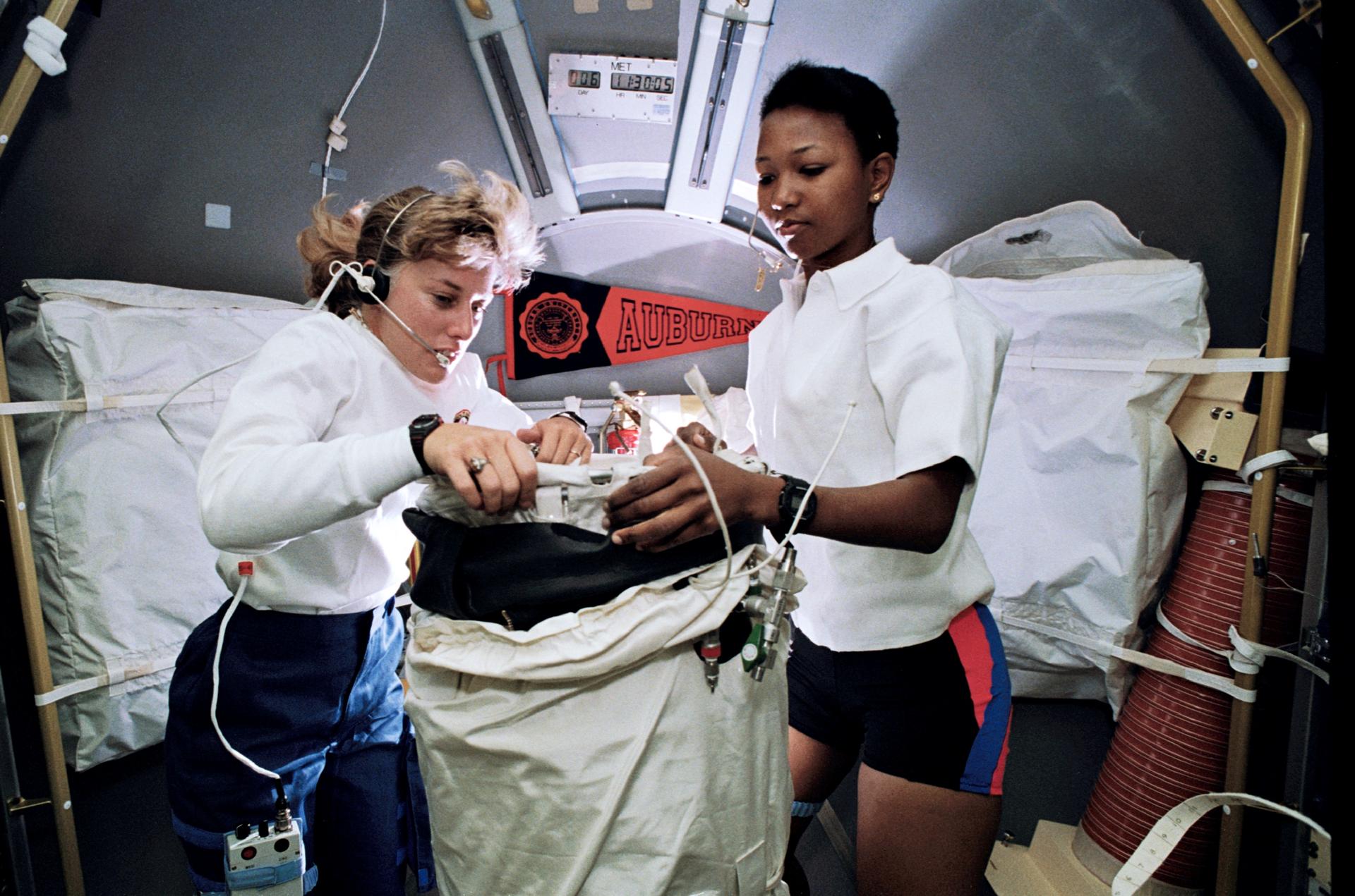 STS-47 Mission Specialists Jan Davis and Mae Jemison prepare to deploy the Lower Body Negative Pressure apparatus in the Science Module.