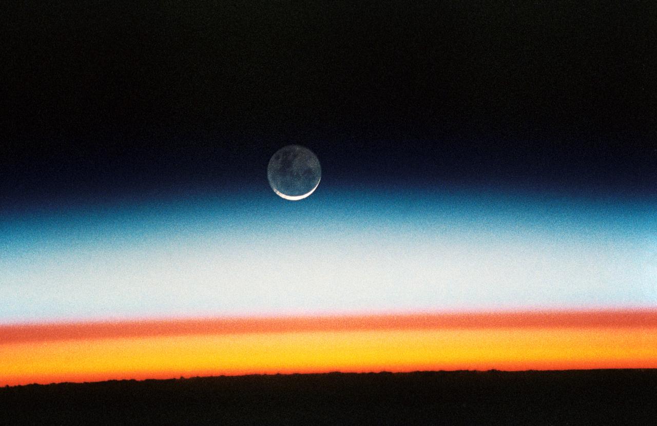 STS052-23-022 (22 Oct.-1 Nov. 1992) --- As the Space Shuttle Columbia orbited Earth in an easterly direction over the Indian Ocean, moonrise was followed quickly by sunrise. The photograph was taken from an altitude of 285 kilometers (154 nautical miles), over Lake Tanganyika in central Africa. The Sun was still 28 degrees below the horizon and not yet illuminating the dark band of low-level clouds on the limb 1,850 kilometers (l,000 nautical miles) away. Ranging from 13--18 kilometers above these low-level clouds is a brown layer at the tropical tropopause. A tropopause is a major atmospheric temperature inversion which isolates the troposphere from the stratosphere and effectively concentrates particulate from both above and below this level.