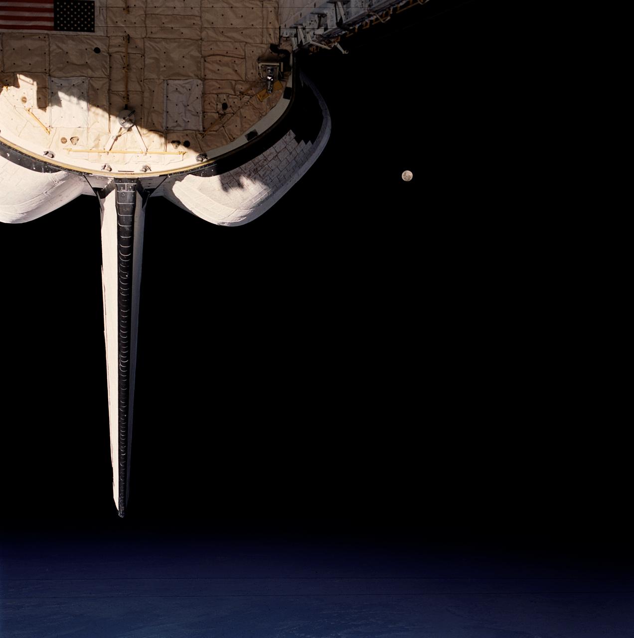 STS053-105-002 (2-9 Dec. 1992) --- A crew member onboard the space shuttle Discovery used a 70mm camera to capture this scene of a full Moon backdropped against the blackness of space. Part of Discovery's aft cargo bay and clouds over an ocean complete the scene.