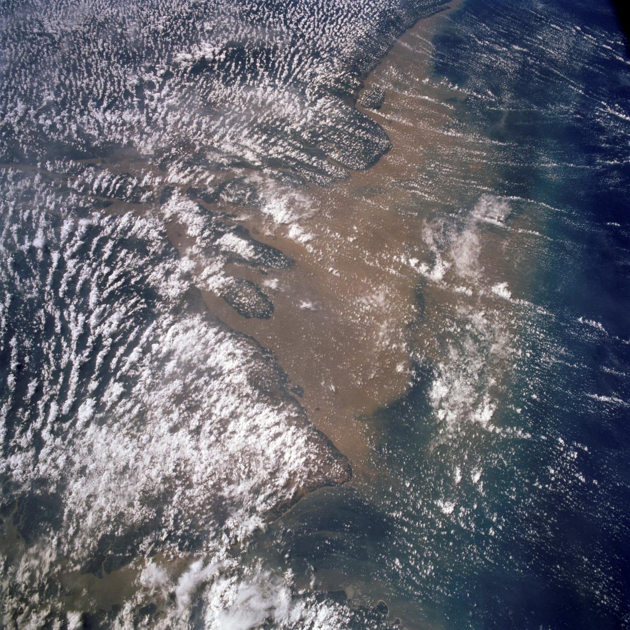 STS058-107-083 (18 Oct.-1 Nov. 1993) --- A near-nadir view of the mouth of the Amazon River, that shows all signs of being a relatively healthy system, breathing and exhaling. The well-developed cumulus field over the forested areas on both the north and south sides of the river (the view is slightly to the west) shows that good evapotranspiration is underway. The change in the cloud field from the moisture influx from the Atlantic (the cloud fields over the ocean are parallel to the wind direction) to perpendicular cloud fields over the land surface are normal. This change in direction is caused by the increased surface roughness over the land area. The plume of the river, although turbid, is no more or less turbid than it has been reported since the Portuguese first rounded Brasil's coast at the end of the 15th Century.