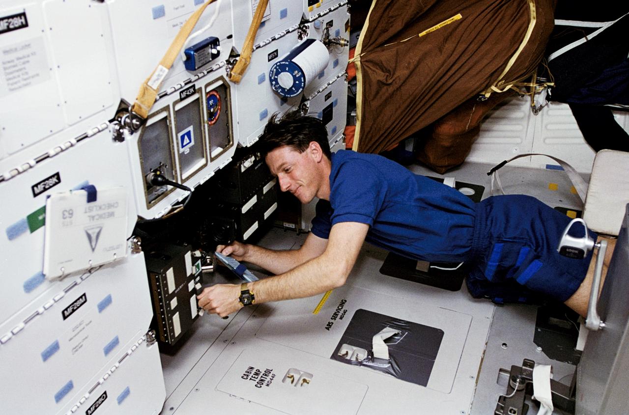 STS063-29-002 (3-11 Feb. 1995) --- On the Space Shuttle Discovery's middeck, astronaut C. Michael Foale, mission specialist, checks on the Solid Surface Combustion Experiment (SSCE). Foale was joined by four other NASA astronauts James D. Wetherbee, commander; Eileen M. Collins, pilot; Bernard A. Harris, Jr., payload commander; Janice E. Voss, mission specialist, and a Russian cosmonaut, Vladimir G. Titov; for eight days of research in Earth-orbit.