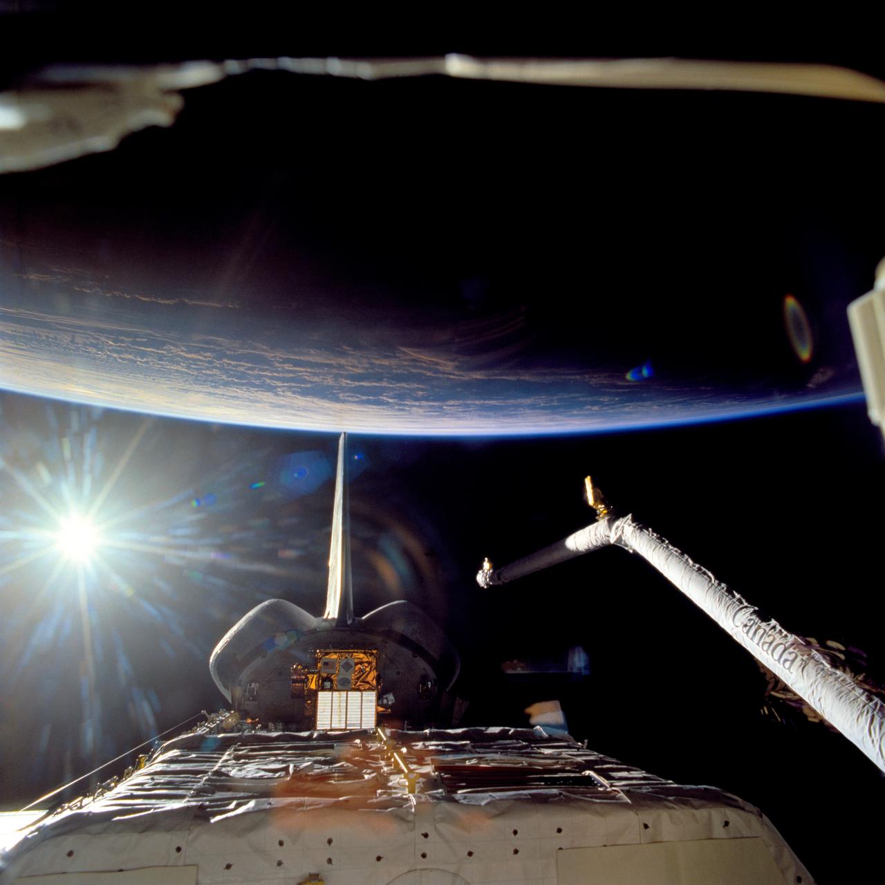 STS063-716-025 (9 Feb. 1995) --- In tail-to Earth mode, the Space Shuttle Discovery is backdropped against dark space, Sunburst and massive clouds over the ocean.  The Spartan 204 is visible in the cargo bay. This is one of 16 still photographs released by the NASA Johnson Space Center (JSC) Public Affairs Office (PAO) on February 14, 1995.  Onboard Discovery were astronauts James D. Wetherbee, mission commander; Eileen M. Collins, pilot; Bernard A. Harris, Jr., payload commander; mission specialists C. Michael Foale, Janice E. Voss, and cosmonaut Vladimir G. Titov.