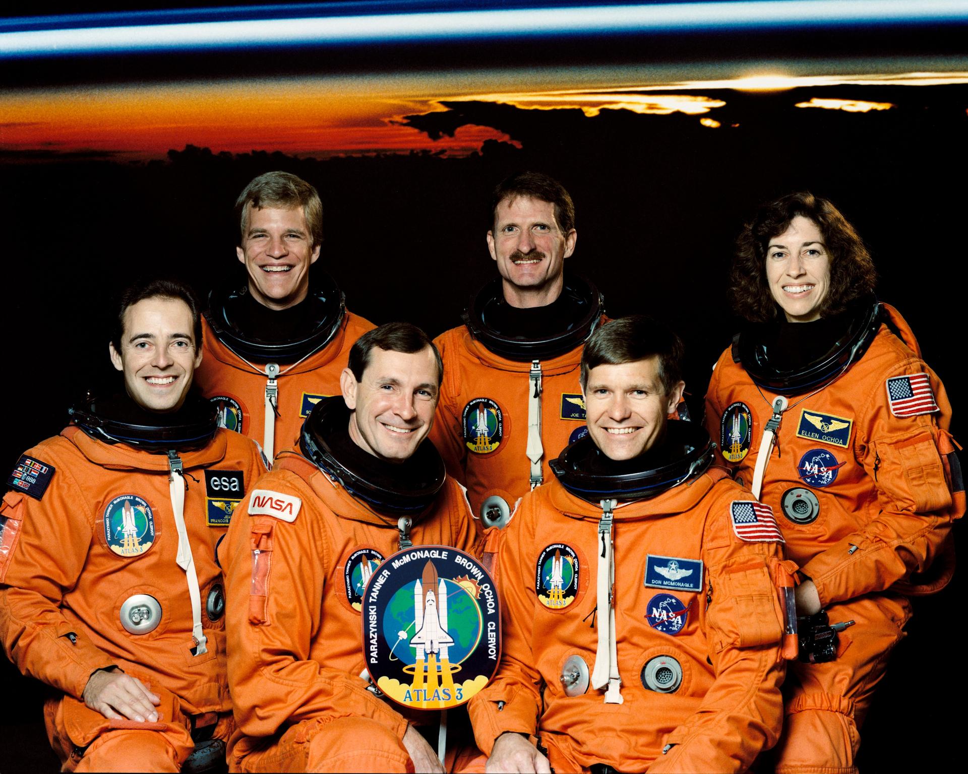 Five men and one woman in orange spacesuits pose for crew photo.