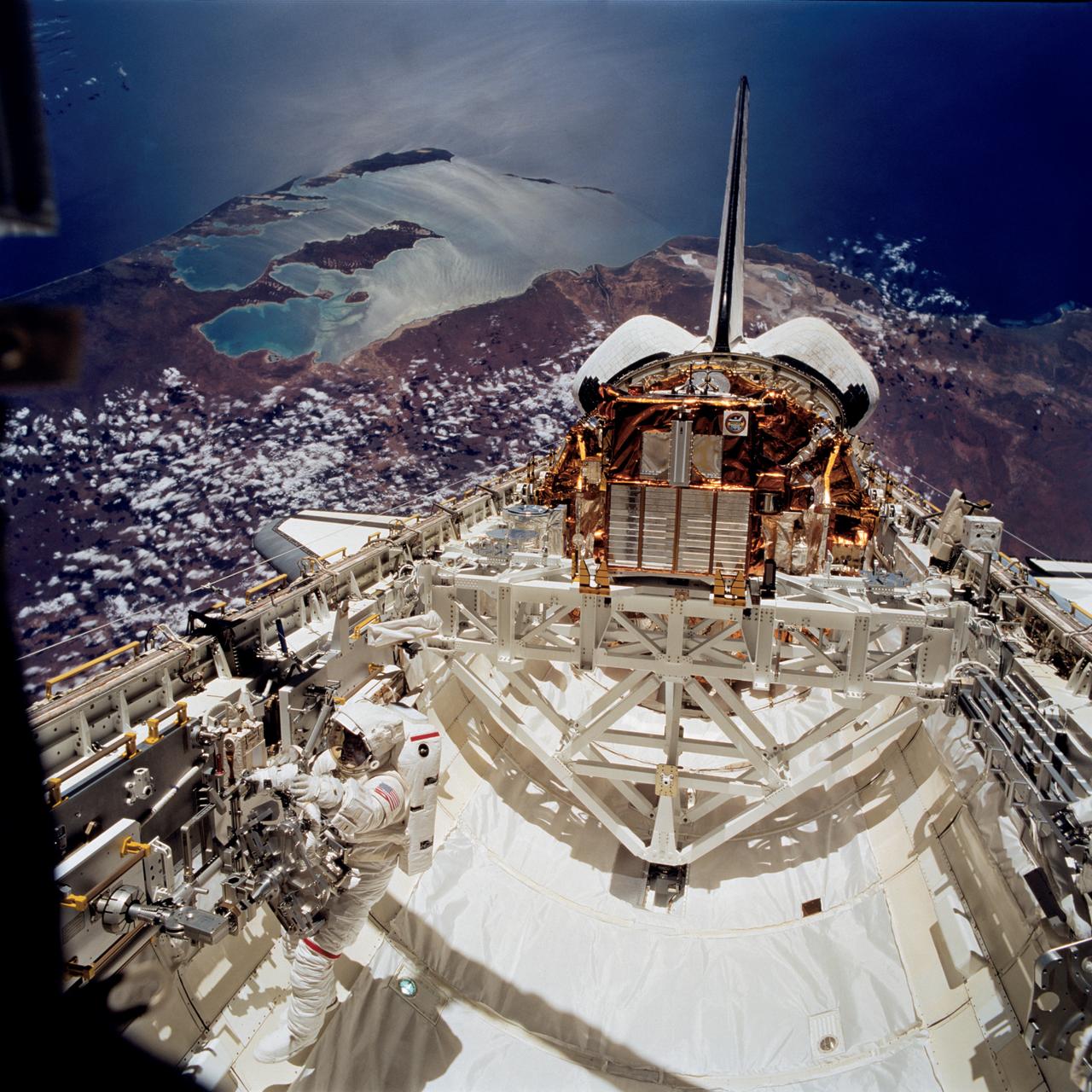 STS072-740-044 (17 Jan. 1996) --- Backdropped against Australia's Shark Bay, this panoramic scene of the Space Shuttle Endeavour in Earth-orbit was recorded during the mission's second Extravehicular Activity (EVA-2) on January 17, 1996. Astronaut Leroy Chiao works with a Mobile Foot Restraint (MFR) at bottom left. The Japanese Space Flyer Unit (SFU) satellite and the Office of Aeronautics and Space Technology (OAST) Flyer satellite are seen in their stowed positions in the aft cargo bay.
