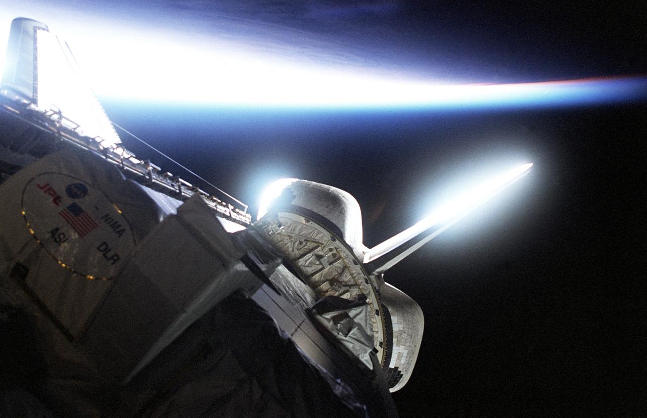 STS099-315-031 (11-22 February 2000) --- The Space Shuttle Endeavour orbits Earth with its lengthy SRTM mast at work (out of frame). Part of the SRTM payload is silhouetted in the cargo bay. Airglow effect of Earth's atmosphere makes for interesting light and color display.