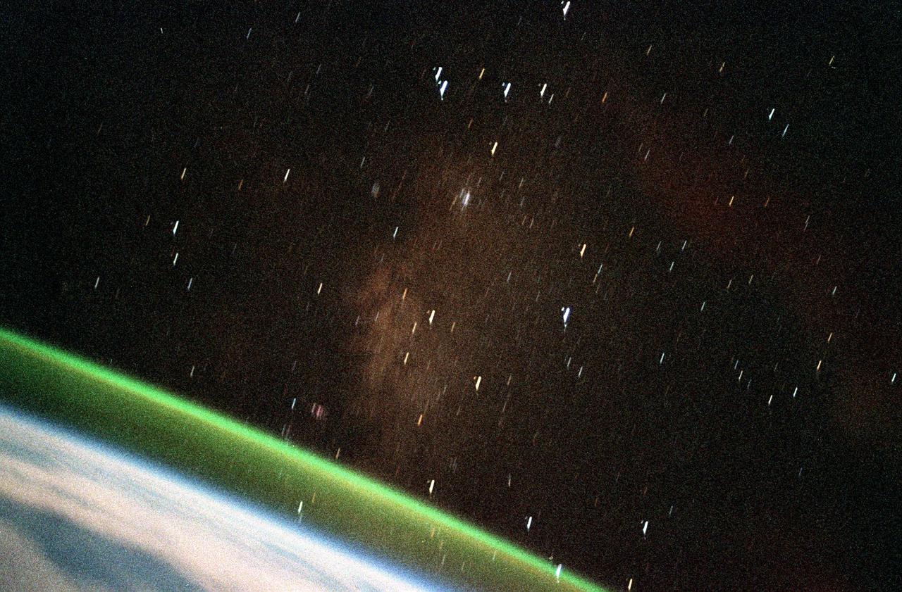 STS099-355-024 (11-22 February 2000) -- Two separate atmospheric optical phenomena appear in this 35mm photograph captured from the Space Shuttle Endeavour.  The thin greenish band above the horizon is airglow;  radiation emitted by the atmosphere from a layer about 30-kilometers thick and about 100-kilometers' altitude.  The predominant emission in airglow is the green 5577-Angstrom wavelength emission from atomic oxygen atoms, which is also the predominant emission from the aurora.  A yellow-orange color is also seen in airglow, which is the emission of the 5800-Angstrom wavelength from sodium atoms.  Airglow is always present in the atmosphere; it results from the recombination of molecules that have been broken apart by solar radiation during the day.  But airglow  is so faint that it can only be seen at night by looking &quot;edge on&quot; at the emission layer, such as the view that astronauts have in Earth orbit.  The other phenomenon in the photo appears to be a faint, diffuse red aurora.  Red aurora occur from about 200 kilometers to as high as 500 kilometers altitude only in the auroral zones at polar latitudes.  They are caused by the emission of 6300- Angstrom wavelength light from oxygen atoms that have been raised to a higher energy level (excited) by collisions with energetic electrons pouring down from the Earth's magnetosphere.  The light is emitted when the atoms return to their original unexcited state.  With the red light so faint in this picture, scientists are led to believe that the flux density of incoming electrons was small.  Also, since there is no green aurora below the red, that indicates that the energy of the incoming electrons was low - higher energy electrons would penetrate deeper into the atmosphere where the green aurora is energized.
