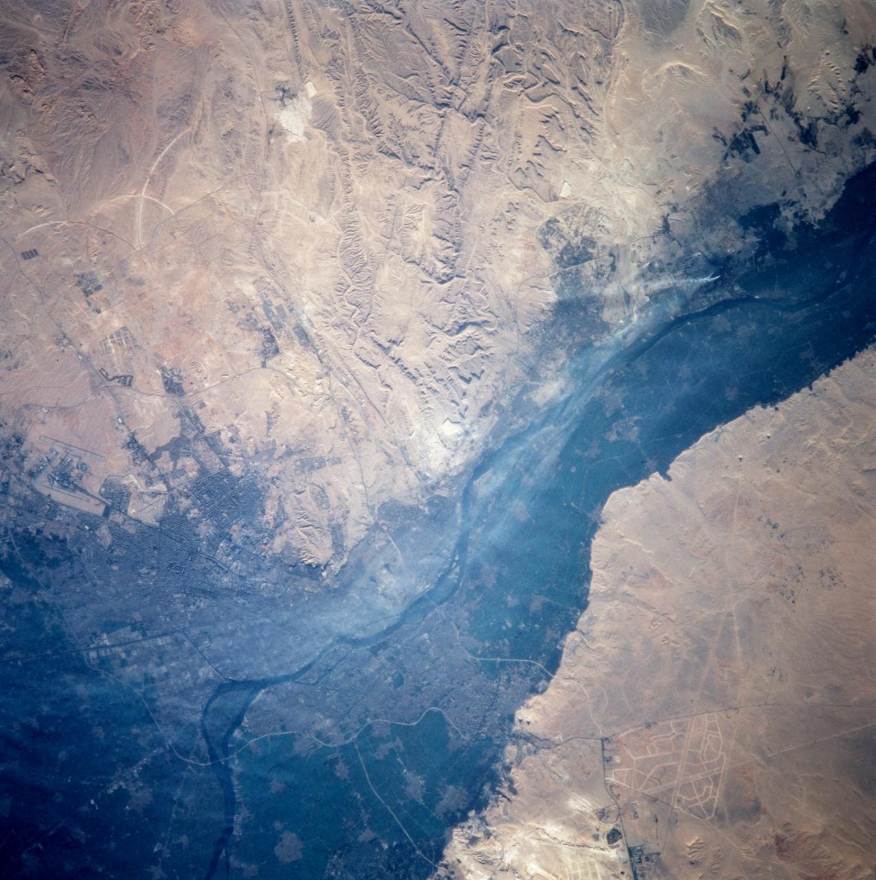 STS099-714-060 (11-22 February 2000) ---One of the STS-99 astronauts aboard the Space Shuttle Endeavour recorded this 70mm image of Cairo, one of the fastest growing cities in the world.  The city is moving outside the dark-colored Nile valley into the surrounding desert.  New developments are side by side with ancient monuments.  The pyramids at Giza are highlighted by their shadows and the new development in the desert to the South is outlined by lighter-colored roads.  Further south of the Giza pyramids on the west side of the Nile River are the Step and Bent Pyramids, respectively.