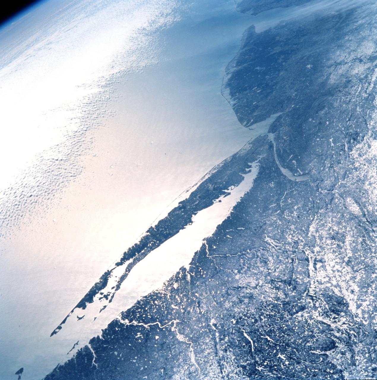 STS099-727-045 (11-22 February 2000) ---One of the astronauts aboard the Space Shuttle Endeavour for the STS-99 mission recorded this 70mm image of Long Island, New York. The entire length of Long Island is visible in partial sunglint from Lower Bay to Block Island Sound. According to geologists, the origin and shape of Long Island are due to continental collision and glaciers that once dominated the landscape. A collision between North America and Africa about 300 million years ago caused the Appalachian Mountains to rise, they say. Streams carried sediment from the eroding Appalachians and also carved a valley that would one day become Long Island Sound. The scientists went on to say that retreating ice sheets 22,000 years ago allowed the land to rebound with the highest points becoming Long Island.