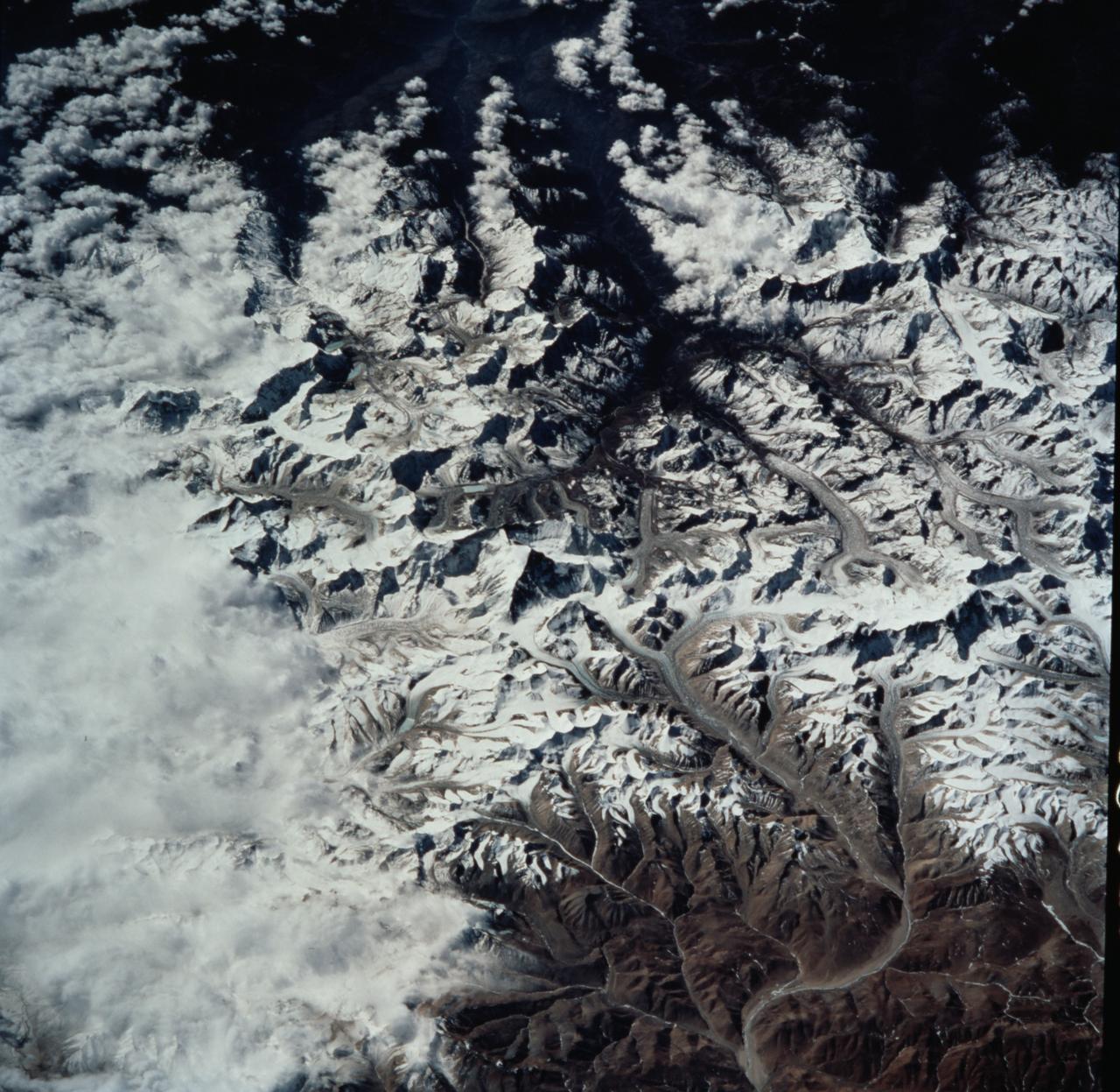 STS099-735-046 (11-22 February 2000) ---Mt. Everest (29,028 feet or 8,848 meters), is featured in the center of this 70mm frame photographed by one of the STS-99 crew members.  Everest, also called Qomolangma Feng, is just north of the border between Nepal and China.  The Himalayas and the Tibetan Plateau are products of the collision of the Indian and Eurasian tectonic plates.  With the continuing northward march of India, the crust of the Earth has become thicker and the Tibetan Plateau has been uplifted to an average elevation of about 15,000 feet.  According to NASA scientists studying the STS-99 imagery, fossil-bearing limestones are at the summit of the mountain.  The scientists say that these limestones were deposited beneath the sea around 510 million years ago (Cambrian to Ordovician time).  Glaciers, moraines, and outwash plains are spectacularly displayed.  Glacial meltwaters in this area feed the Arun River, eventually reaching the Ganges on the plains of India.