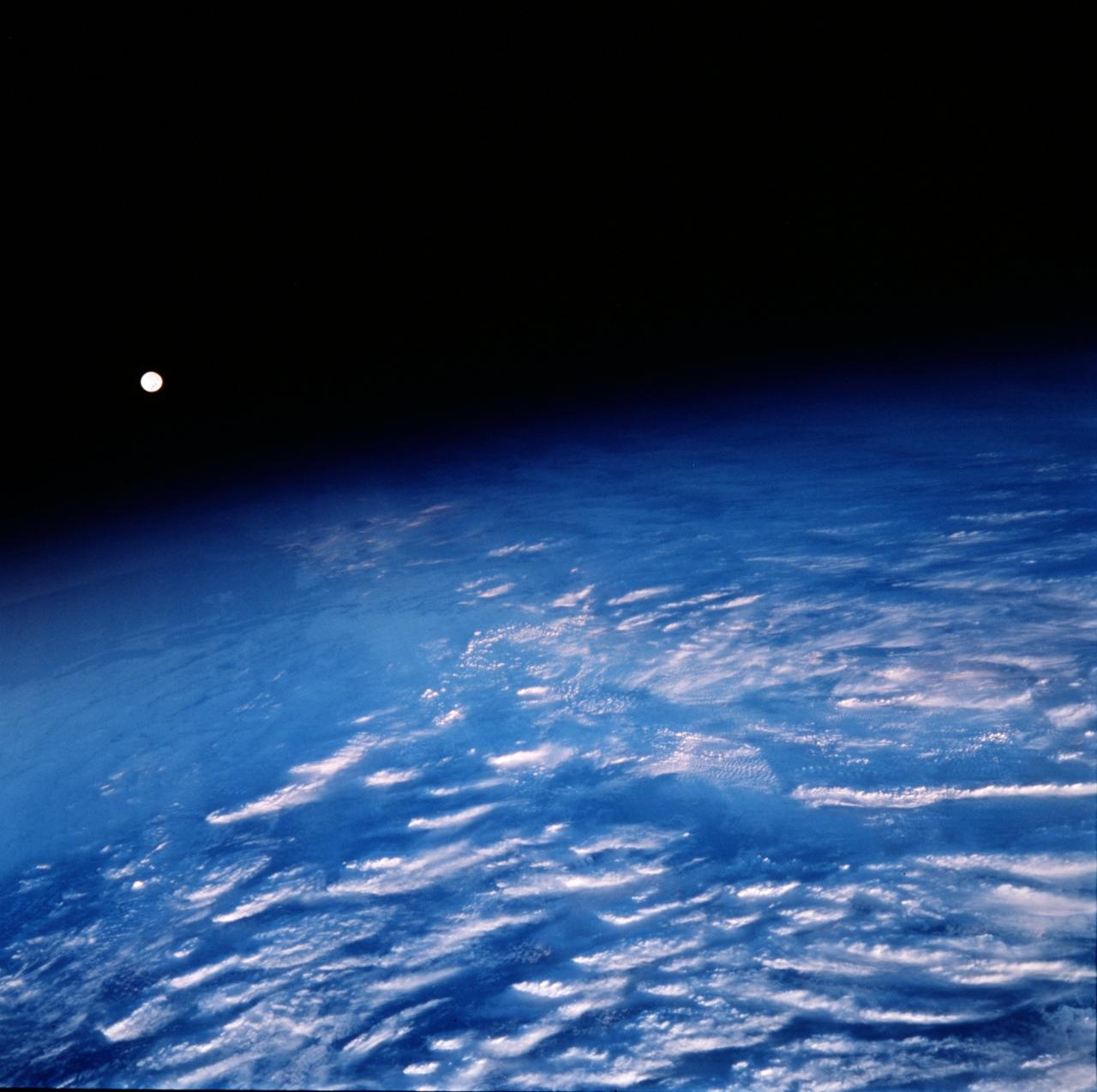 STS099-752-073 (11-22 February 2000) ---As seen by the crew aboard the Space Shuttle Endeavour, the Moon appears above Earth's limb with clouds in the foreground.  Moonlit clouds and sunlit clouds are shown in the same scene.