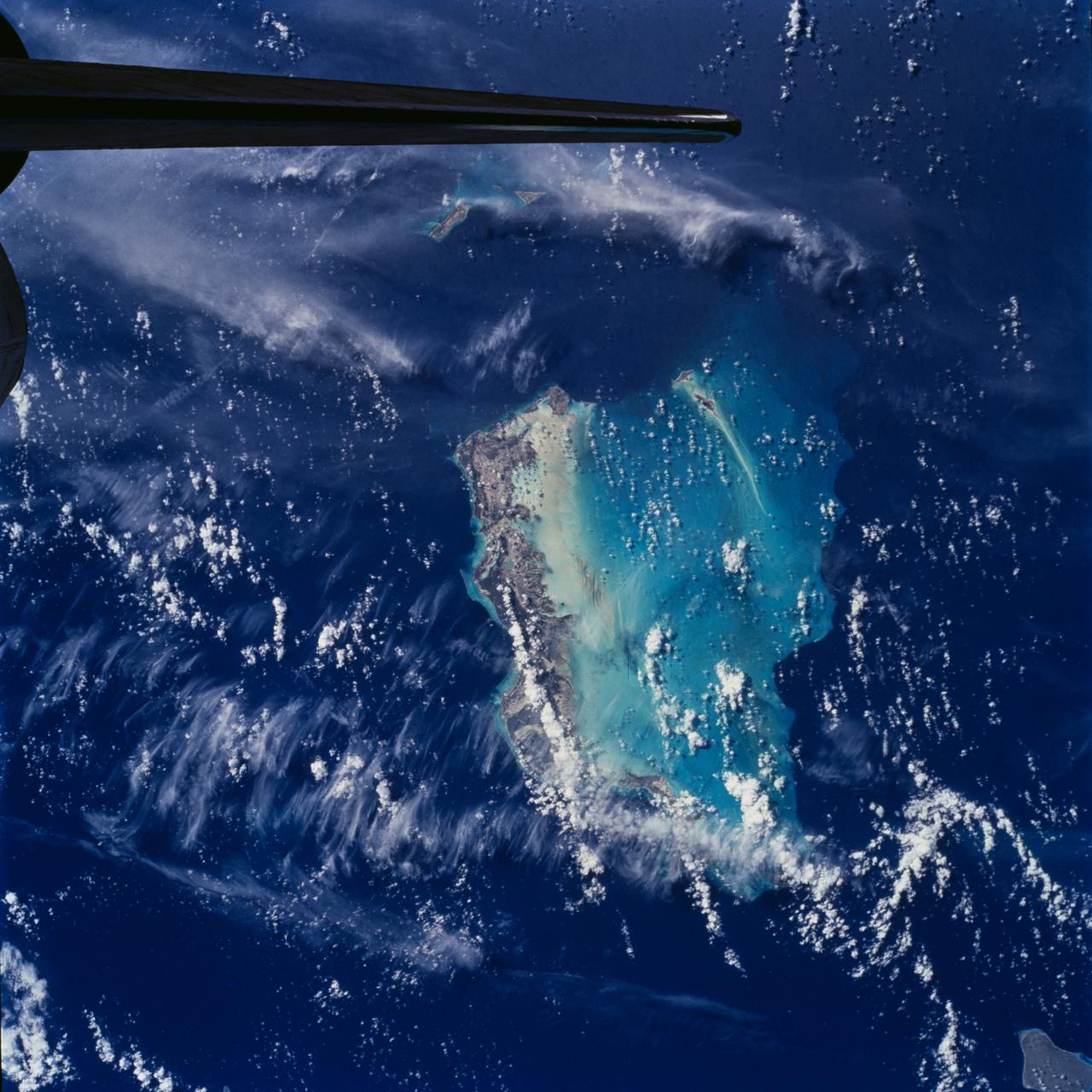 STS100-708-78 (19 April-1 May 2001) --- Southwest of the Bahamas and north of Hispaniola lie the Turks and Caicos Islands, photographed by the astronaut/cosmonaut crew aboard the Earth-orbiting Space Shuttle Endeavour. In this view, the extensive shallow water areas of Caicos Bank (turquoise blue) dominate to the south of the Caicos Islands.  Caicos Bank covers an area of 7,680 square kilometers (1.9 million acres).  The coral reefs of Caicos are primarily along the north deep water edge of the islands, and in a barrier along the south margin of the bank.  The area is known for its marine caves and blowholes.  To the east of Caicos Bank, near the tail of the Shuttle, is the island of Grand Turk, part of the much smaller Turks Bank.  The channel that runs between the two banks is more than 2,200 meters (1.4 miles) deep.