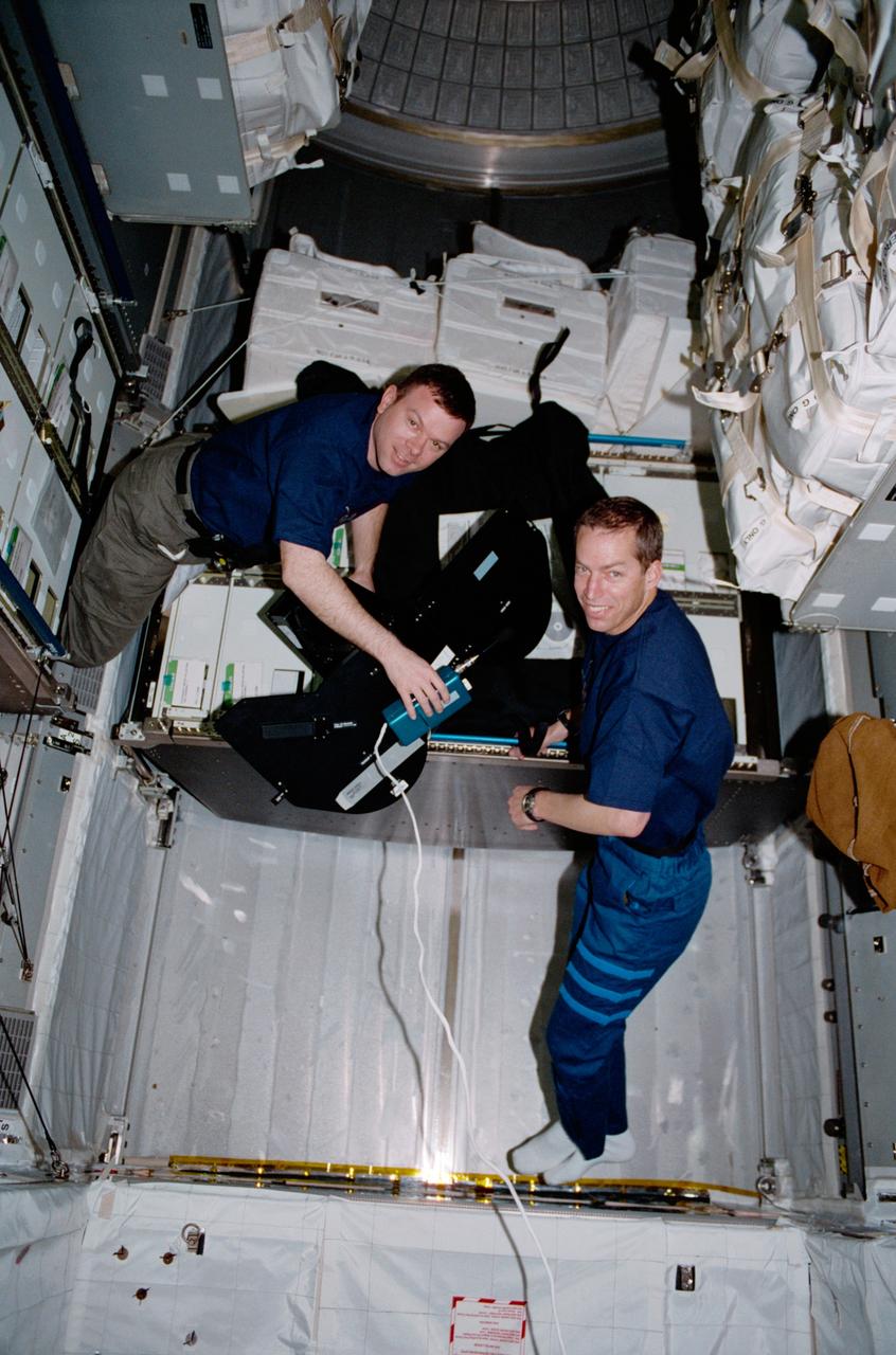 STS102-319-035 (8 - 21 March 2001) --- Astronauts James M. Kelly (left) and James D. Wetherbee, pilot and commander, respectively, for the STS-102 mission, participate in the movement of supplies inside Leonardo, the Italian Space Agency-built Multipurpose Logistics Module (MPLM). Here, the two are handling a film magazine for the IMAX camera.