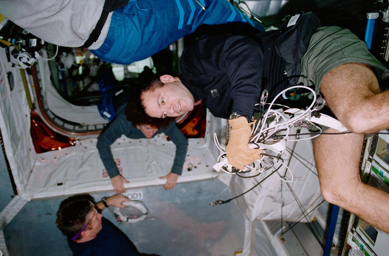 STS102-320-025 (8-21 March 2001) --- Astronaut Paul W. Richards, STS-102 mission specialist, is photographed inside Leonardo, the Italian Space Agency-built Multi-Purpose Logistics Module (MPLM). Leonardo is the first of three such pressurized modules that will serve as the International Space Stations (ISS) moving vans, carrying laboratory racks filled with equipment, experiments and supplies to and from the station aboard the space shuttle. In the background are astronauts William M. (Bill) Shepherd, Expedition One commander, and Susan J. Helms, Expedition Two flight engineer.
