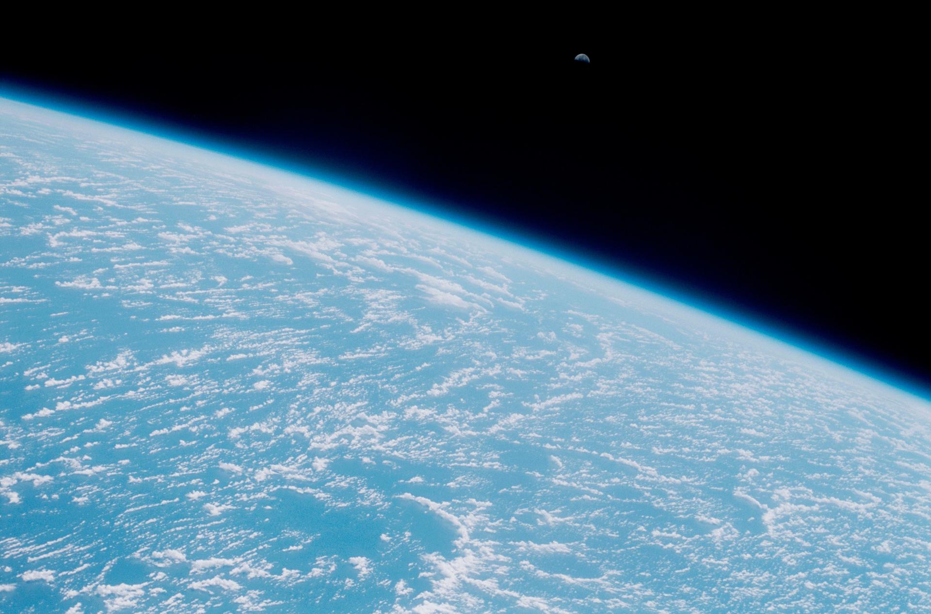 Moon rise over the Earth viewed from space looking down at the curve of the earth