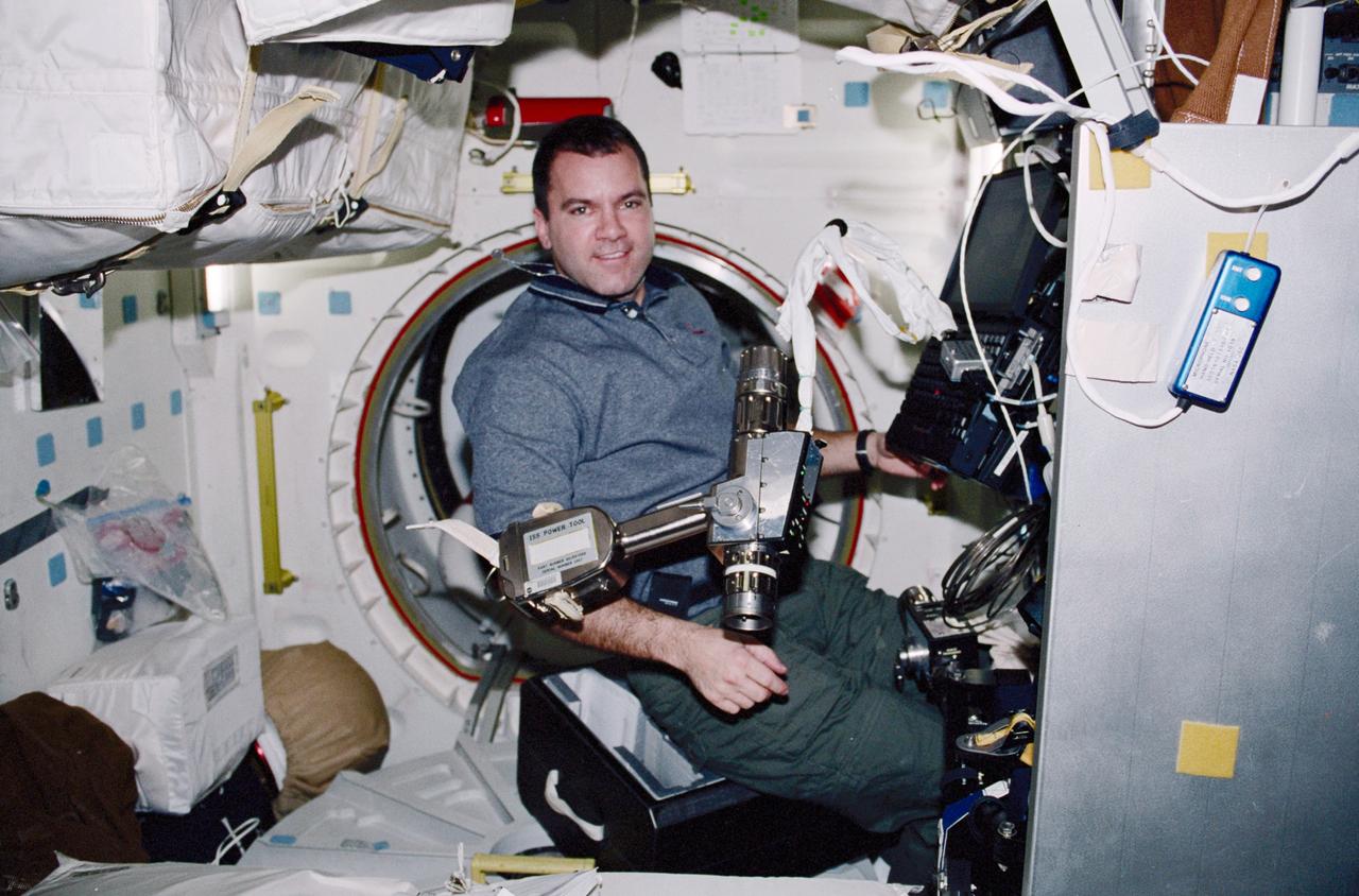 STS102-346-027 (8-21 March 2001) --- Astronaut Paul W. Richards, STS-102 mission specialist, consults data on a lap top computer on the Space Shuttle Discovery’s mid deck. An International Space Station (ISS) pistol grip tool floats near Richards.