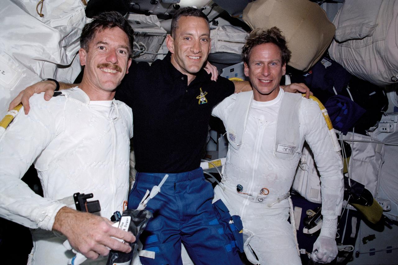 STS104-326-007 (12-24 July 2001) --- The two STS-104 space walkers show their appreciation for the helpful hand of  astronaut Charles O. Hobaugh, pilot, following a space walk.  Astronauts Michael L. Gernhardt (left) and James F. Reilly are wearing the thermal undergarments for the extravehicular mobility unit (EMU) space suit.  On the first two of their three space walks, the two mission specialists exited from the shuttle airlock (pictured).  The crew had brought up and installed the new Quest airlock, which was used for suit-up up and egress for the third and final EVA.
