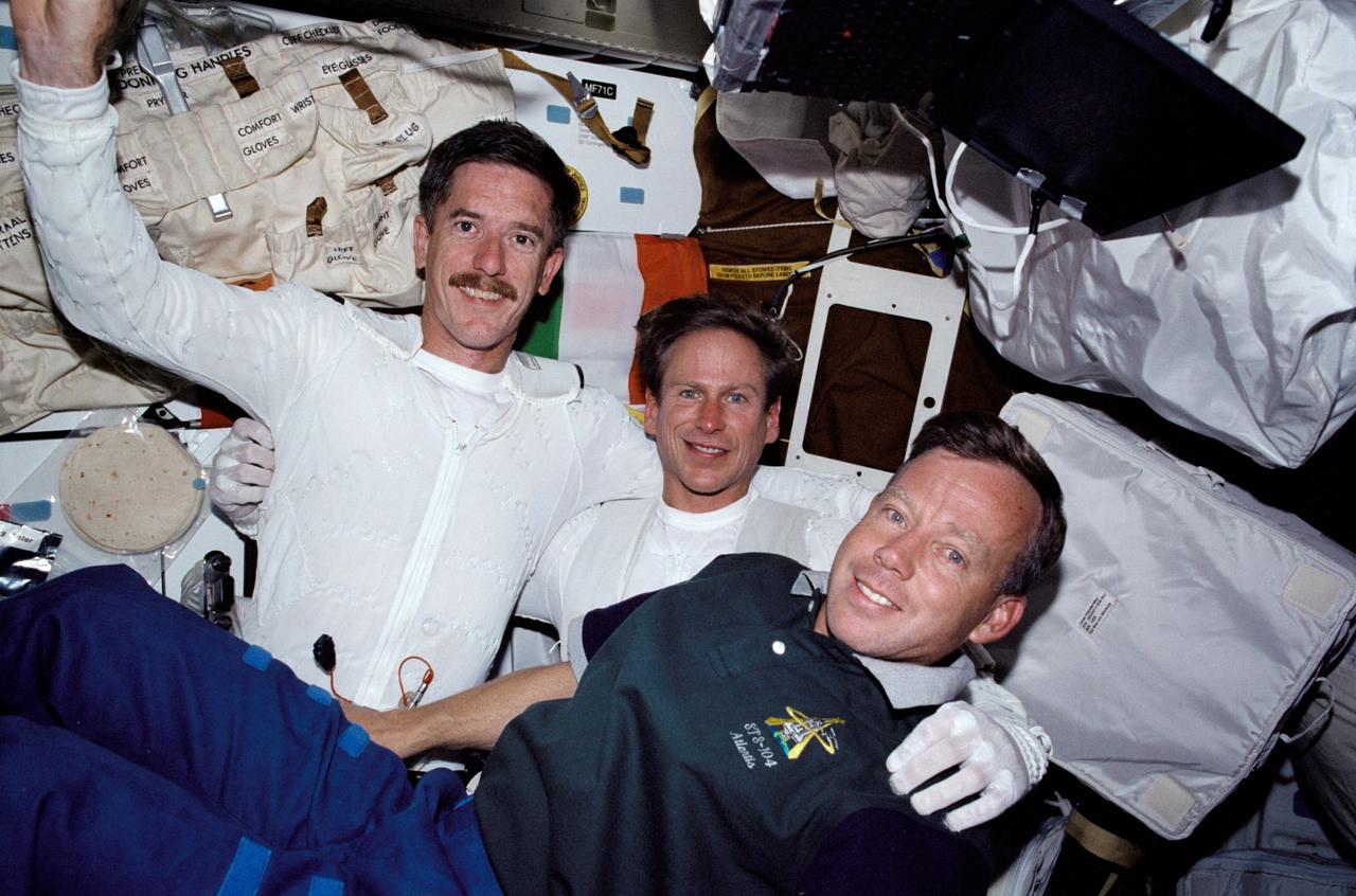 STS104-326-037 (12-24 July 2001) --- Astronaut Steven W. Lindsey (right), STS-104 mission commander, is pictured on Atlantis' mid deck with the assigned space walkers for the 12-day mission following one of their three days of extravehicular activity (EVA).  In the special undergarments for their extravehicular mobility units (EMU) are astronauts James F. Reilly (left) and Michael L. Gernhardt.