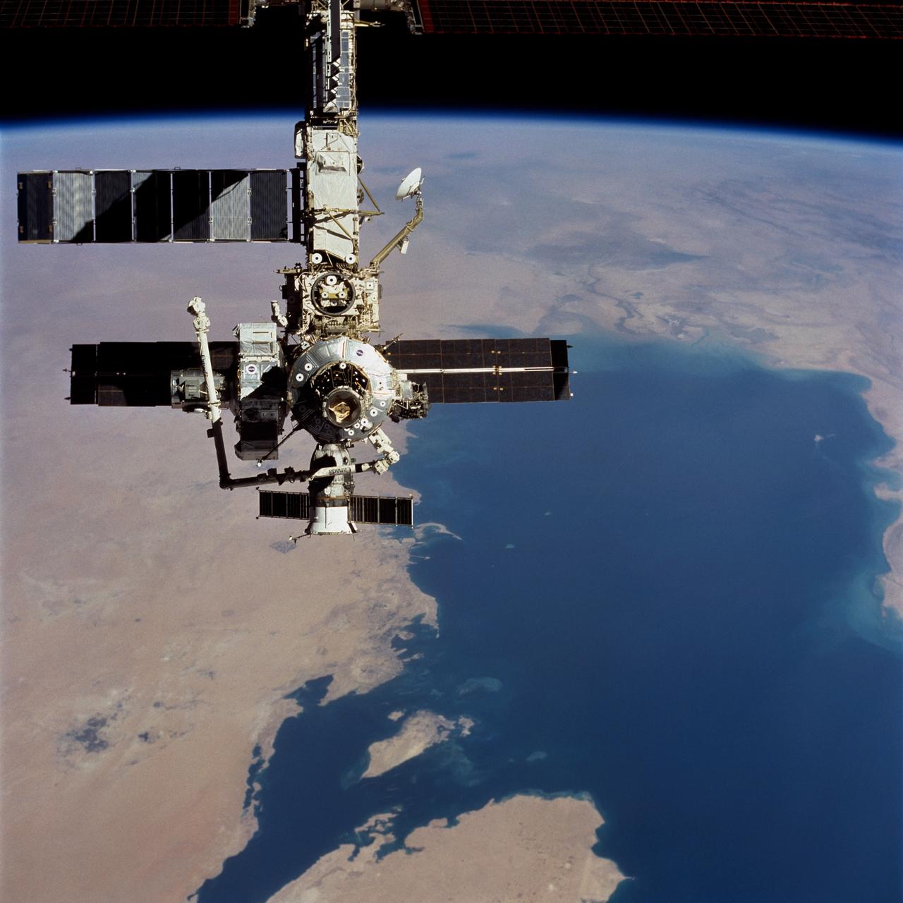 STS104-723-014 (21 July 2001) ---  Backdropped over a wide scene of topography in the Middle  East, the International Space Station (ISS) passes over the Persian Gulf.  The photograph was taken with a 70mm handheld camera during a fly-around inspection by the Space Shuttle Atlantis not long after the two spacecraft separated.  Prominent on the starboard side of the outpost is the newly-installed Quest airlock.