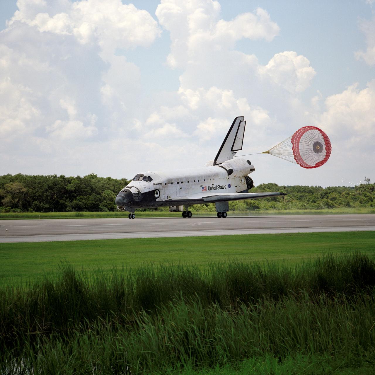 STS105-S-023 (22 Aug. 2001) --- With its drag chute trailing behind, the Space Shuttle Discovery and its crew land on the Kennedy Space Center's Shuttle Landing Facility runway 15. Main gear touchdown was at 2:22:58 p.m. (EDT), Aug. 22, 2001. Wheel stop occurred at 2:24:06 p.m. (EDT). The 11-day, 21-hour, 12-minute STS-105 mission accomplished the goals set for the 11th flight to the International Space Station: swap out of the resident station crew; delivery of equipment, supplies and scientific experiments; and installation of the Early Ammonia Servicer and heater cables for the S0 truss on the Station. Discovery traveled 4.3 million miles on its 30th flight into space, the 106th mission of the Space Shuttle program. The landing was the first of five in 2001 to occur in daylight at KSC. Onboard at landing were STS-105 astronauts Scott J. Horowitz, commander; Frederic W. (Rick) Sturckow, pilot; and Patrick G. Forrester and Daniel T. Barry, both mission specialists; along with the returning Expedition Two crewmembers--cosmonaut Yury V. Usachev, commander; and James S. Voss and Susan J. Helms, both flight engineers.