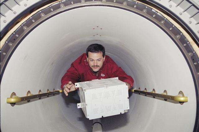 NASA image: Pilot Altman carries a battery through the transfer tunnel during STS-106
