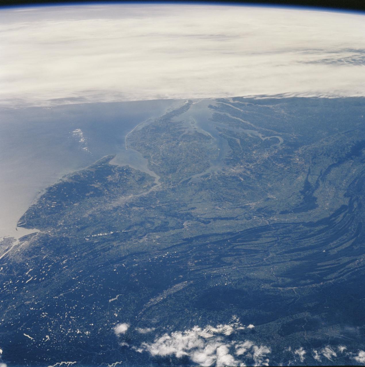 STS106-709-016 (19 September 2000)  --- One of the STS-106 crew members on board the Space Shuttle Atlantis, 204 nautical miles above Earth, used a handheld 70mm camera to photograph this image of the shuttle's cargo bay, a broad band of clouds and a land scene featuring Lake Ontario. Center point coordinates of the ground area are 44 degrees north latitude and 77 degrees west longitude. The Spacehab module, which supports this mission to the International Space Station (ISS), can be seen at the back of the cargo bay. The Atlantis had earlier separated from the ISS after several days of being docked with the orbital outpost.