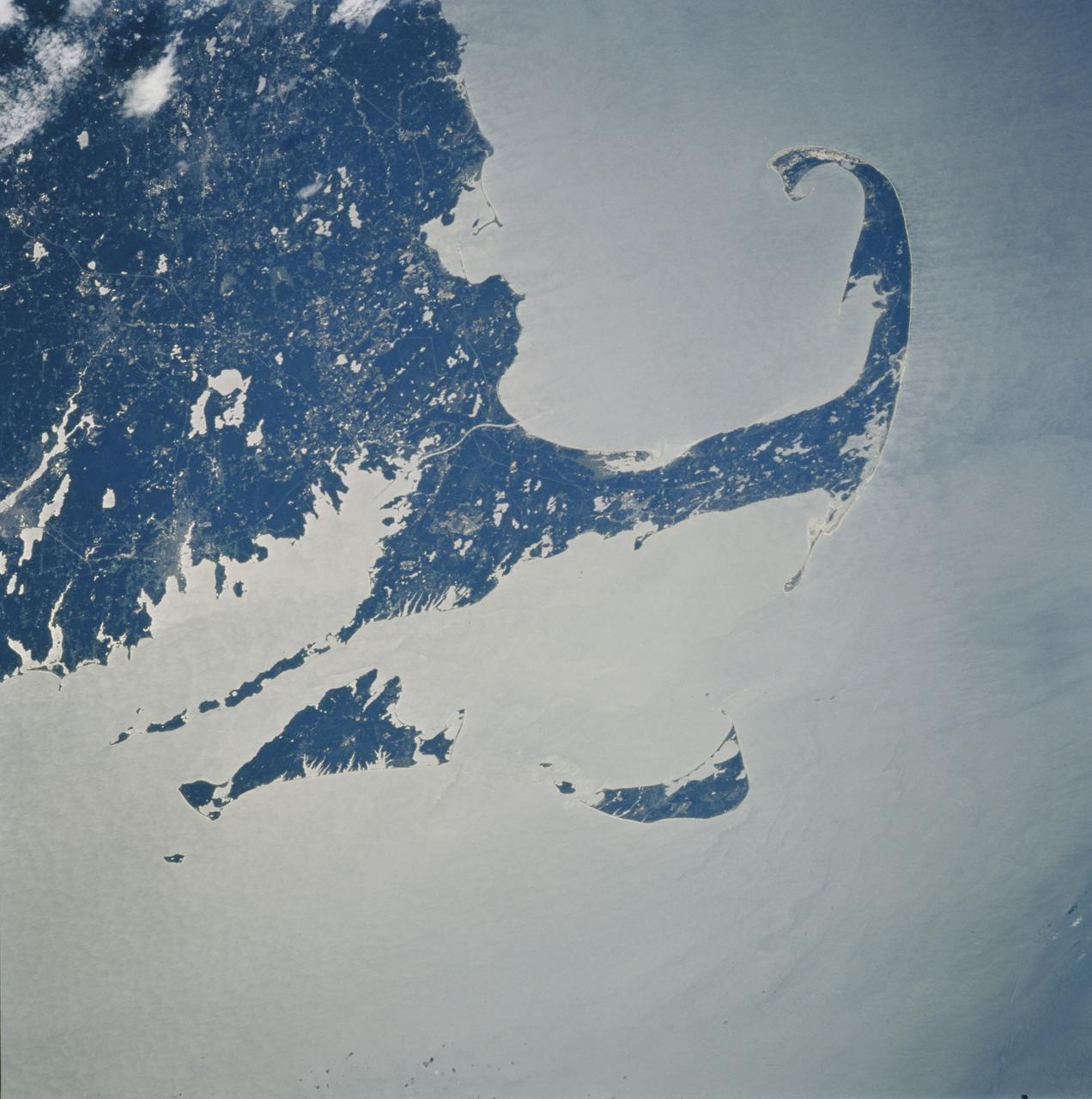 STS106-710-060 (8-20 September 2000) --- One of the STS-106 crew members on board the Space Shuttle Atlantis used a handheld 70mm camera to photograph this image of Cape Cod and parts of Massachusetts.  Partial sun glint highlights the coastline and brings out subtle details in the waters around Massachusetts. The maximum advance of an ice sheet 23,000 years ago is marked by the unique shape of Cape Cod and by the islands of Nantucket and Martha's Vineyard. Rocks and debris left at the edges of the ice fronts made parts of the landscape slightly higher and more resistant to erosion. Glacial retreat and sea level rise covered the lower ground and gave us the more modern coastline that we are familiar with. The city of New Bedford can be located near the coast and just below the circular lakes of Long Pond, Great Quiittacas Pond, and Assawompset Pond.