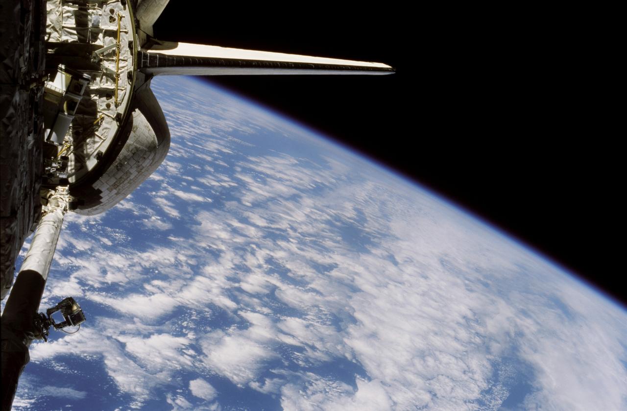 STS116-320-001 (9-22 Dec. 2006) --- Backdropped by the horizon of a blue and white Earth and the blackness of space, part of the Space Shuttle Discovery's aft cargo bay, its vertical stabilizer and orbital maneuvering system (OMS) pods are seen in this image photographed by an STS-116 crewmember onboard the shuttle. This image was recorded with a 35mm film-equipped camera.