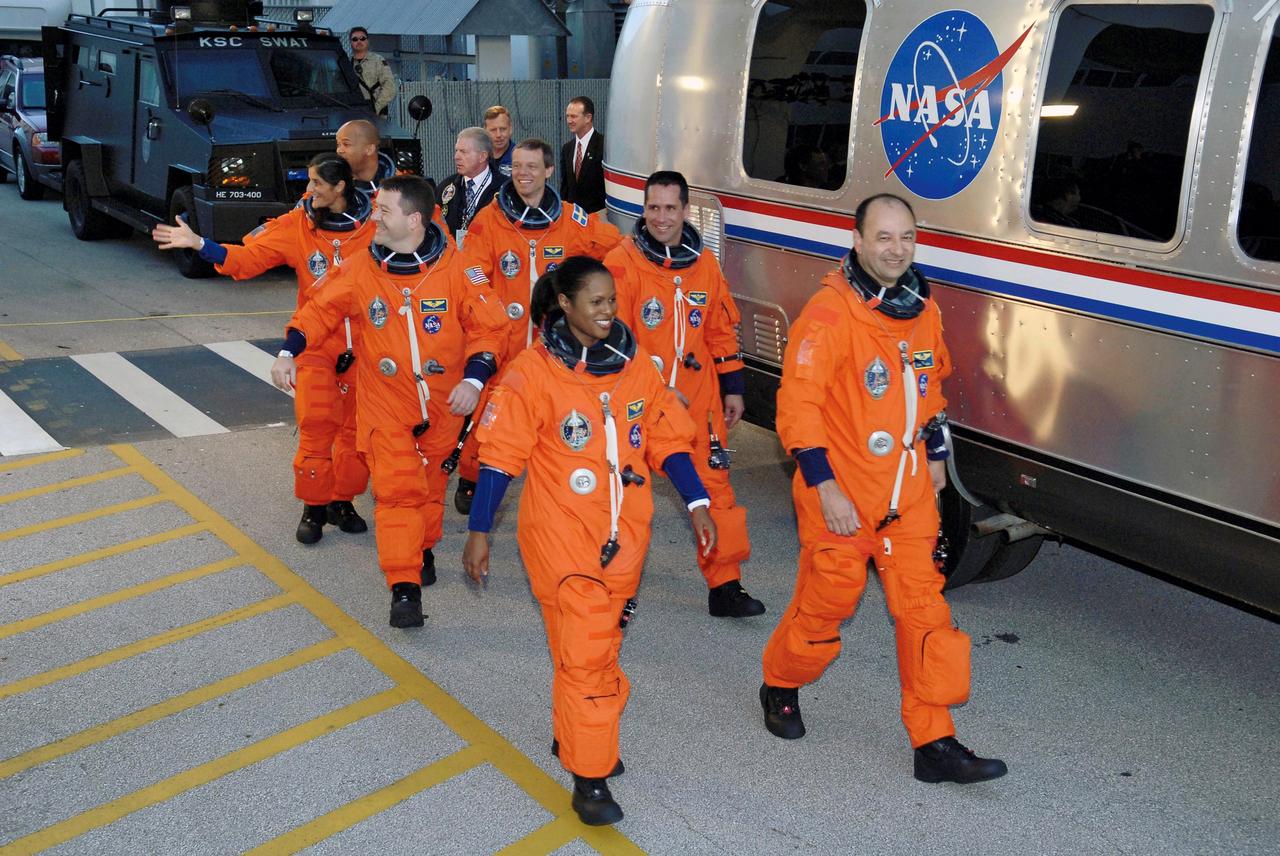 STS116-S-006 (9 Dec. 2006) --- After suiting up, the STS-116 crewmembers exit the Operations and Checkout Building to board the Astrovan, which will take them to launch pad 39B at Kennedy Space Center. On the right (front to back) are astronauts Mark L. Polansky, commander; William S. (Bill) Oefelein, pilot; and Christer Fuglesang, mission specialists representing the European Space Agency (ESA). On the left (front to back) are astronauts Joan E. Higginbotham, Nicholas J. M. Patrick, Sunita L. Williams and Robert L. Curbeam, Jr., all mission specialists. Discovery's seven-member crew will link up with the International Space Station on Monday, Dec. 11, to begin a complex, week-long stay that will rewire the outpost and increase its power supply. During three spacewalks and intricate choreography with ground controllers, the astronauts will bring electrical power on line generated by a giant solar array wing delivered to the station in September.