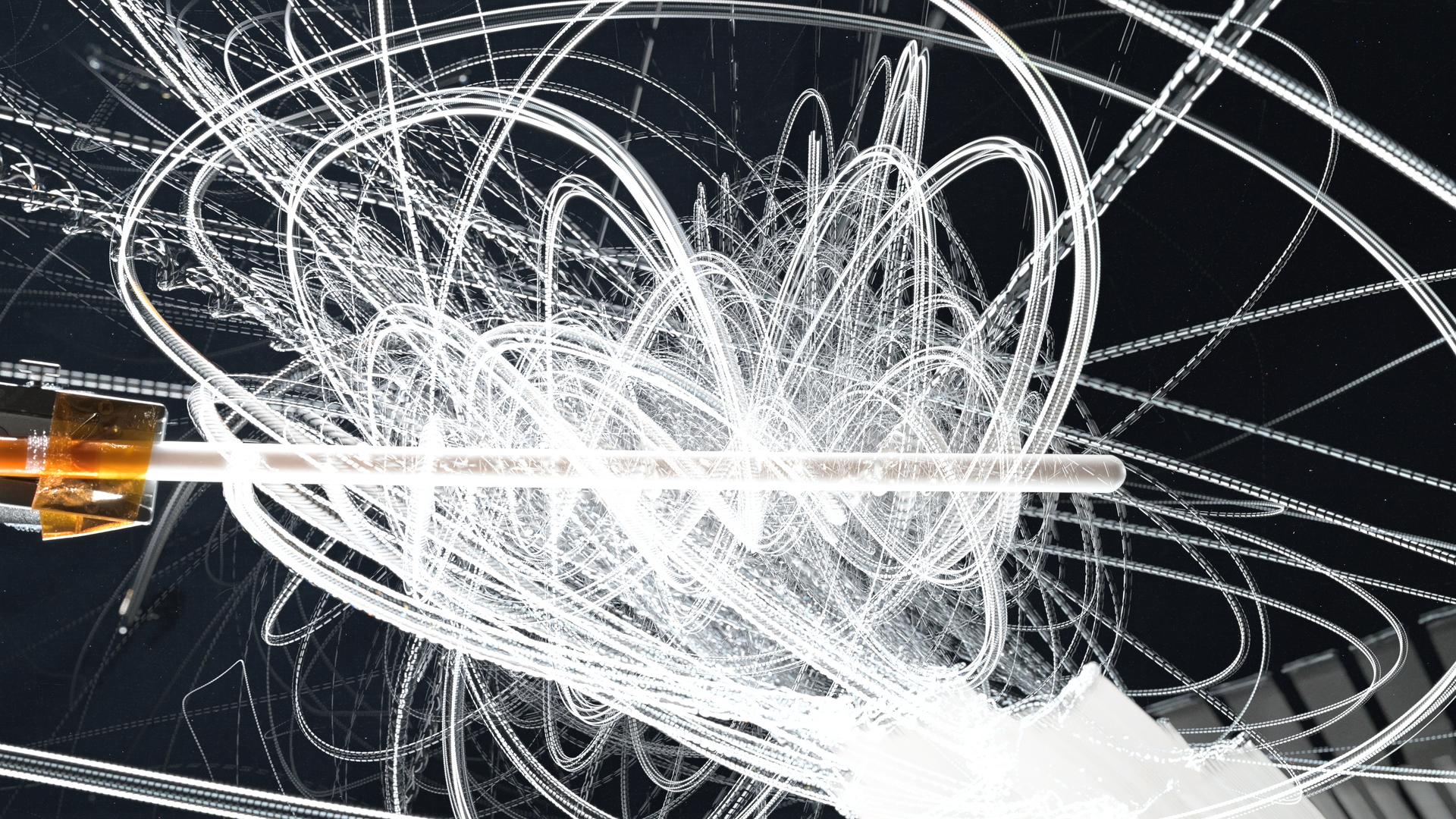 A white knitting needle appears in the middle of the image. Swirling white lines surround the knitting needle, showing the paths of water drops as the move around the needle. The image is a composite of video frames that have been stacked to show the paths of water drops in a single image.