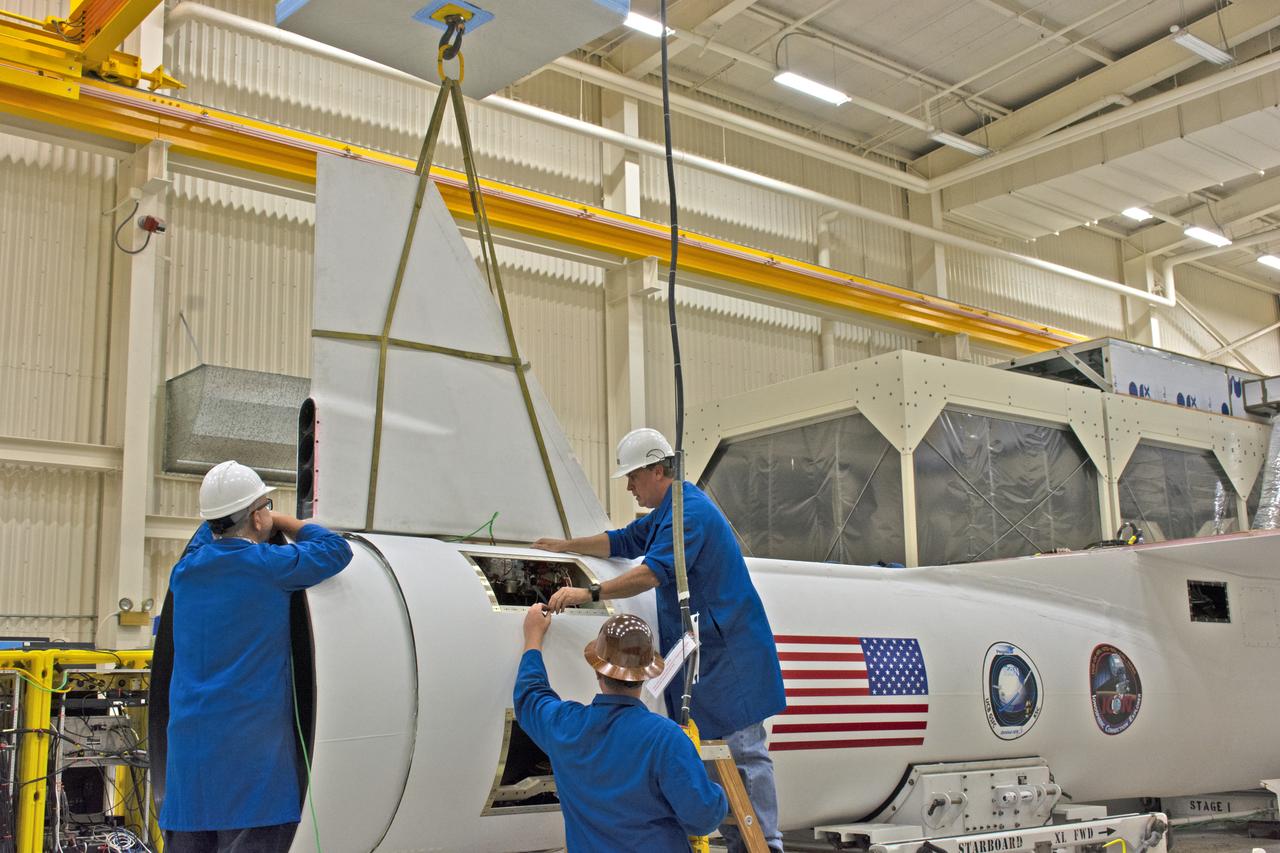 Inside Building 1555 at Vandenberg Air Force Base in California, technicians install the first of two fins on Northrop Grumman's Pegasus XL rocket on July 30, 2018. The Pegasus XL rocket, attached beneath the company's L-1011 Stargazer aircraft, will launch NASA's Ionospheric Connection Explorer (ICON) from the Skid Strip at Cape Canaveral Air Force Station in Florida. Launch is scheduled for Oct. 26. ICON will study the frontier of space - the dynamic zone high in Earth's atmosphere where terrestrial weather from below meets space weather above. The explorer will help determine the physics of Earth's space environment and pave the way for mitigating its effects on our technology, communications systems and society.